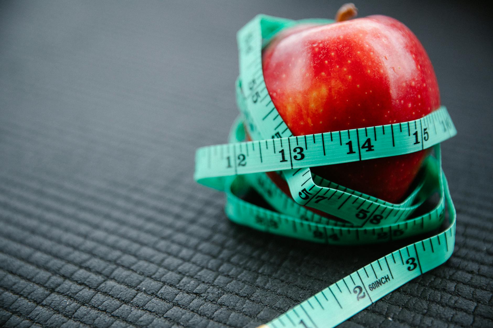 A vibrant red apple encircled by a blue measuring tape, symbolizing health and weight management. - healthy weight loss