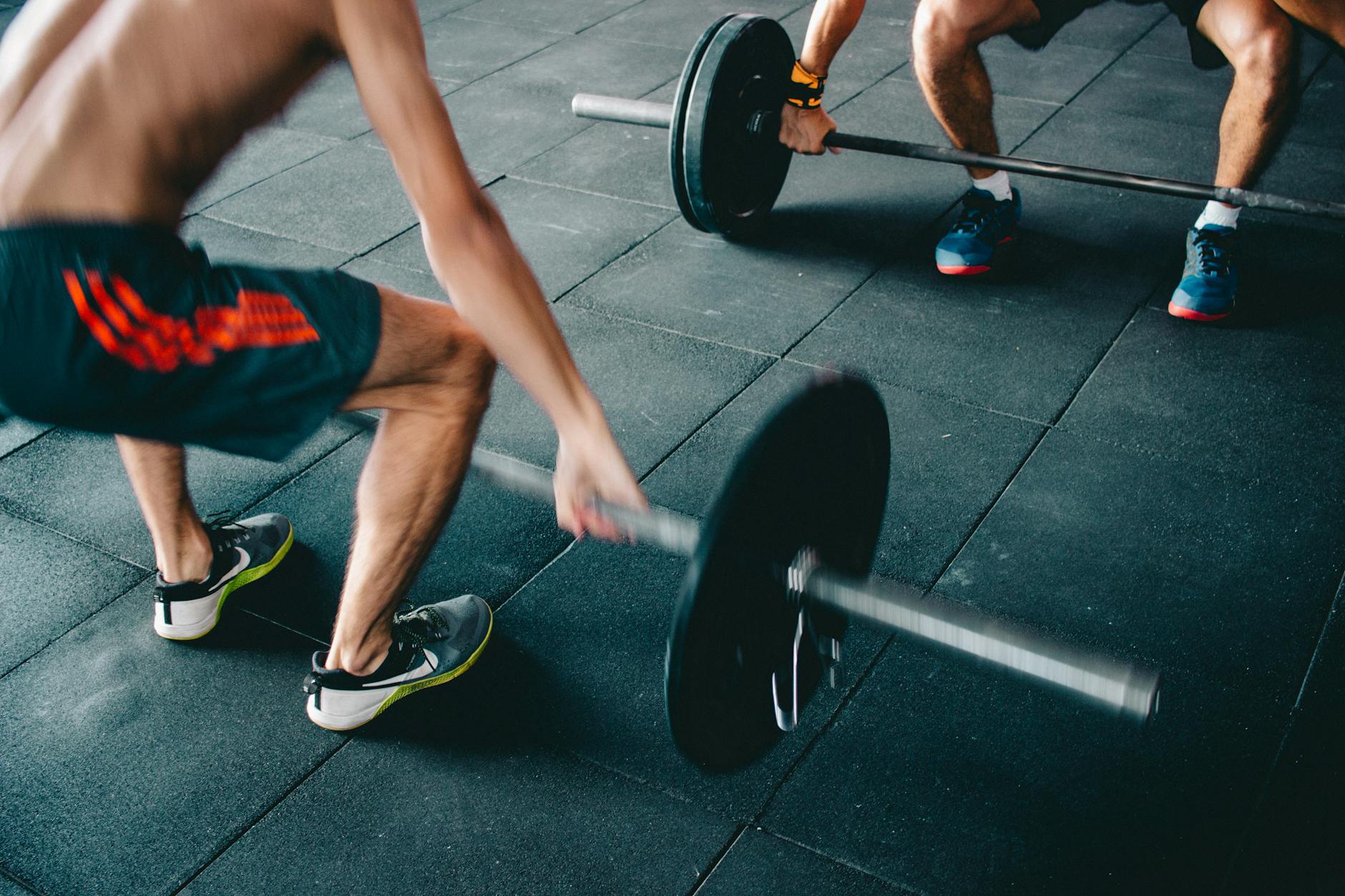 Two men lifting barbells showing strength and effort in a gym setting. - hiit fat burning