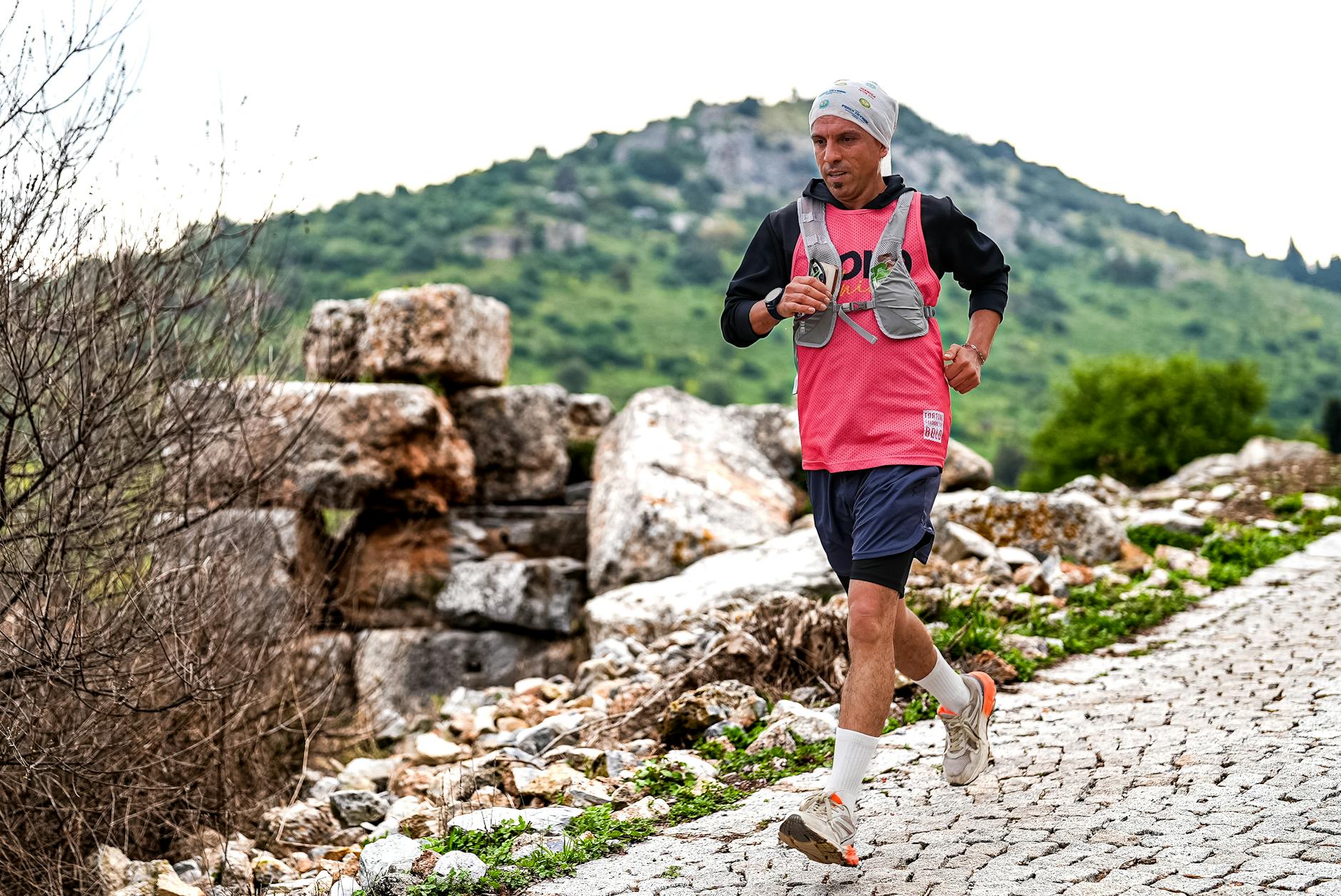 Athlete running on rocky terrain in İzmir, showcasing determination and endurance with scenic mountain backdrop. - hiking endurance training