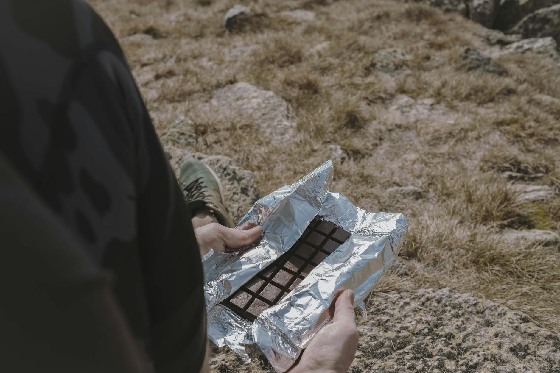 Person enjoying a chocolate bar while hiking in Kosciuszko National Park, Australia. - hiking nutrition tips