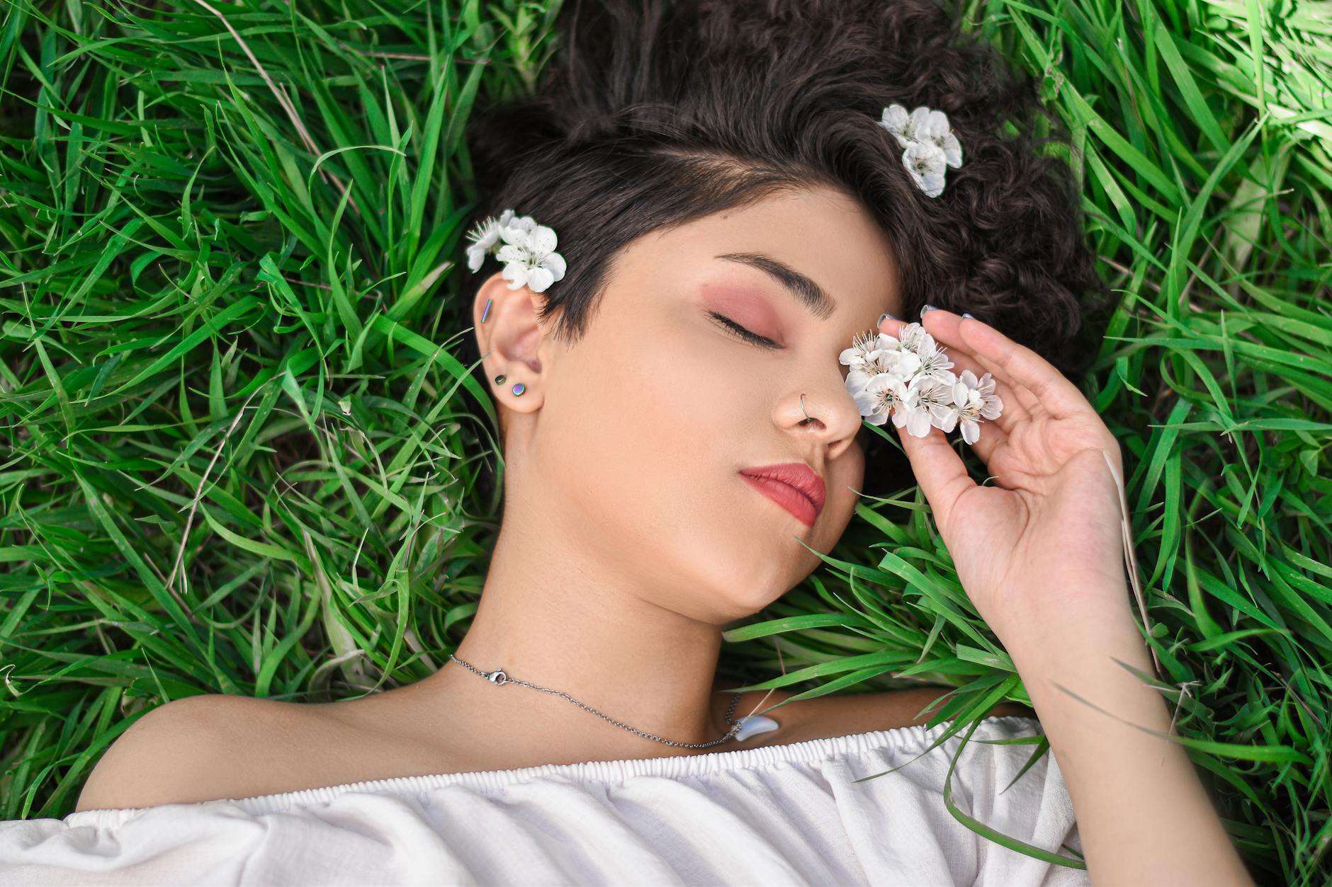 Serene woman lying in grass with flowers, embodying tranquility and nature's beauty. - hormone balance spring