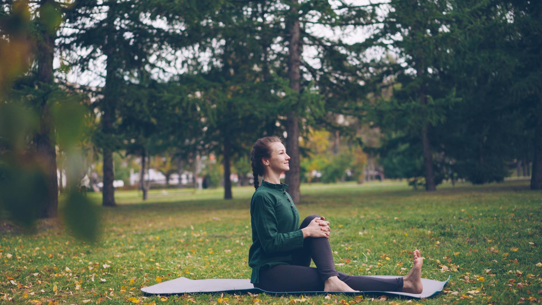 Woman practicing yoga outdoors in a serene park, surrounded by lush greenery. - improve posture