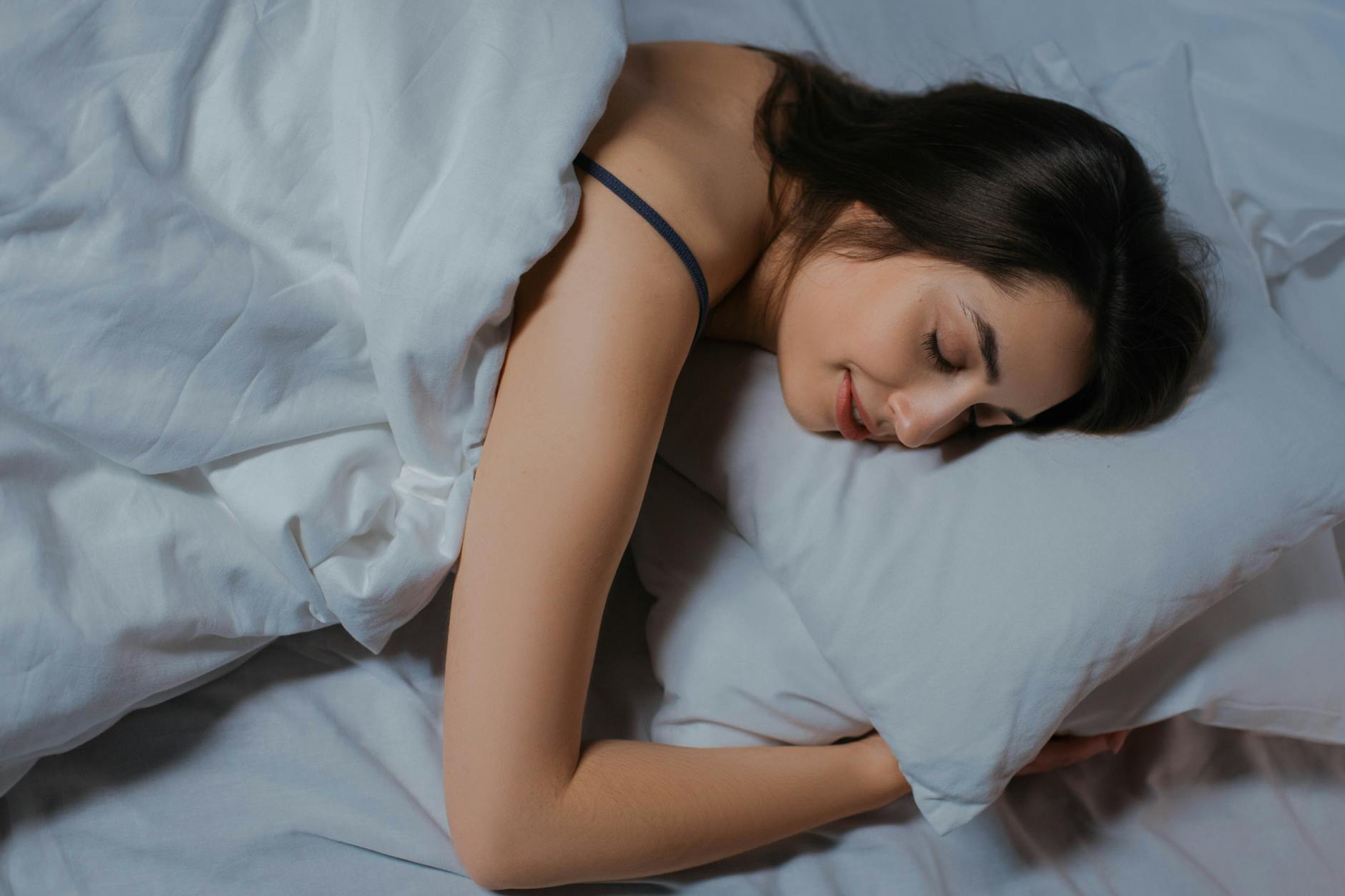 Serene young woman sleeping in cozy bed with white linens. Peaceful and relaxed. - improve sleep quality