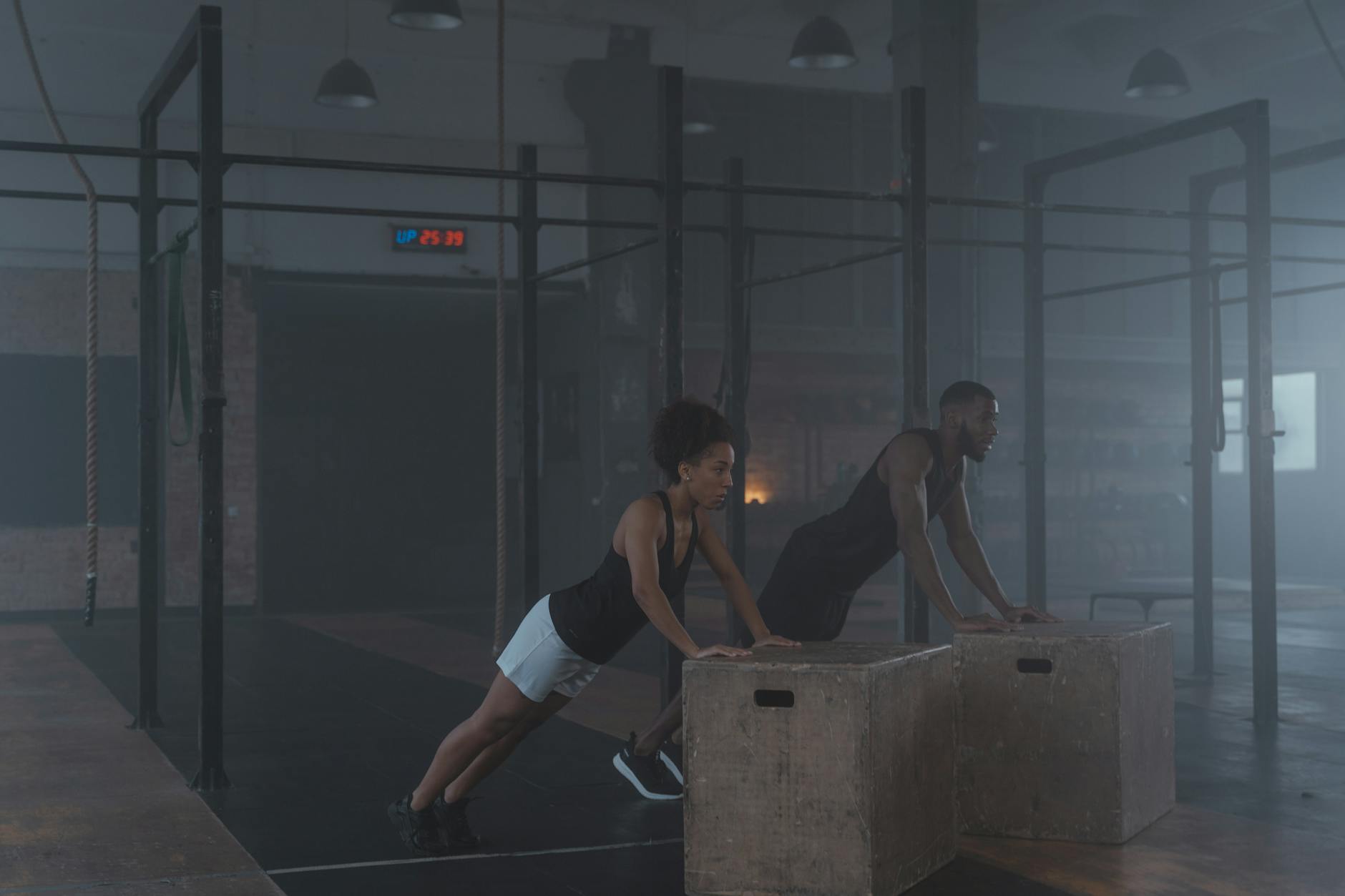 Two individuals engaging in strength training exercises indoors, showcasing fitness and endurance. - intermediate hiit workout