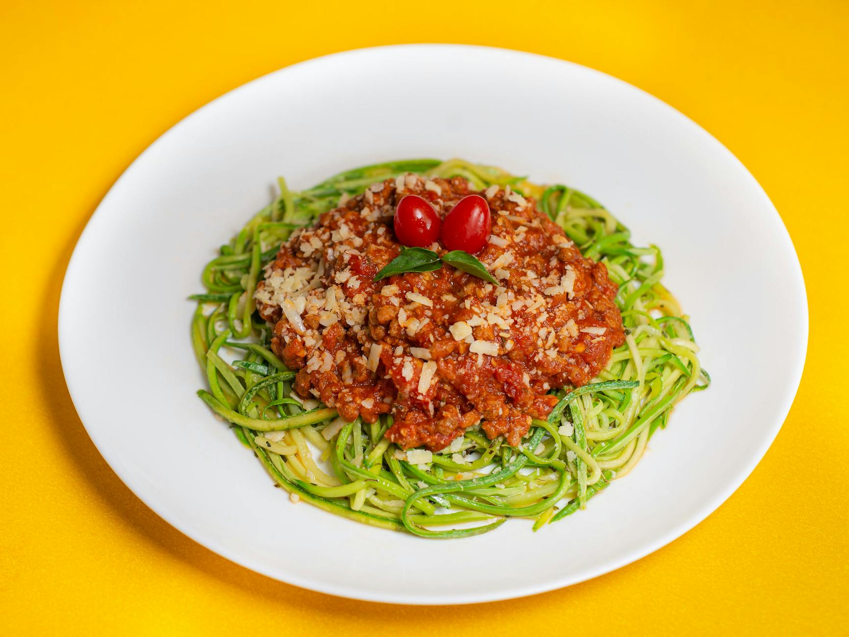 A vibrant dish featuring zucchini noodles topped with savory Bolognese and cherry tomatoes. - low fat low carb