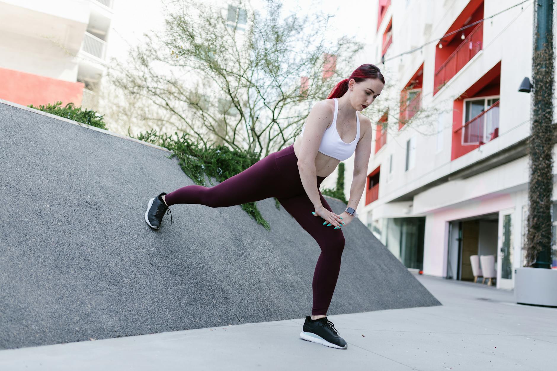 A woman wearing activewear stretches on a ramp in an outdoor urban setting, promoting fitness. - low impact spring workouts