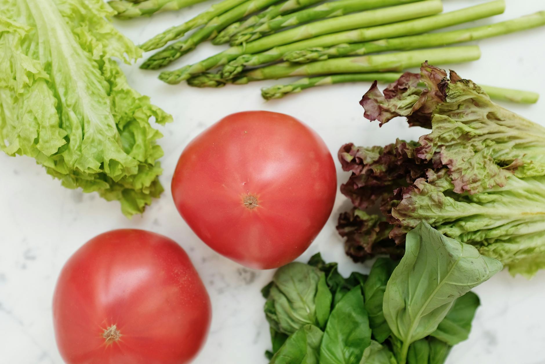 Close-up of fresh vegetables including lettuce, tomatoes, and asparagus for healthy cooking. - macronutrient balance spring
