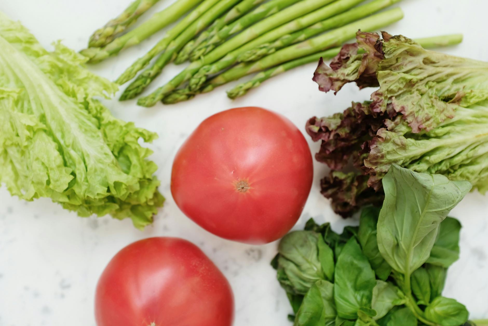 Top view of fresh asparagus, lettuce, basil, and tomatoes, highlighting healthy and nutritious ingredients. - macronutrient balance spring