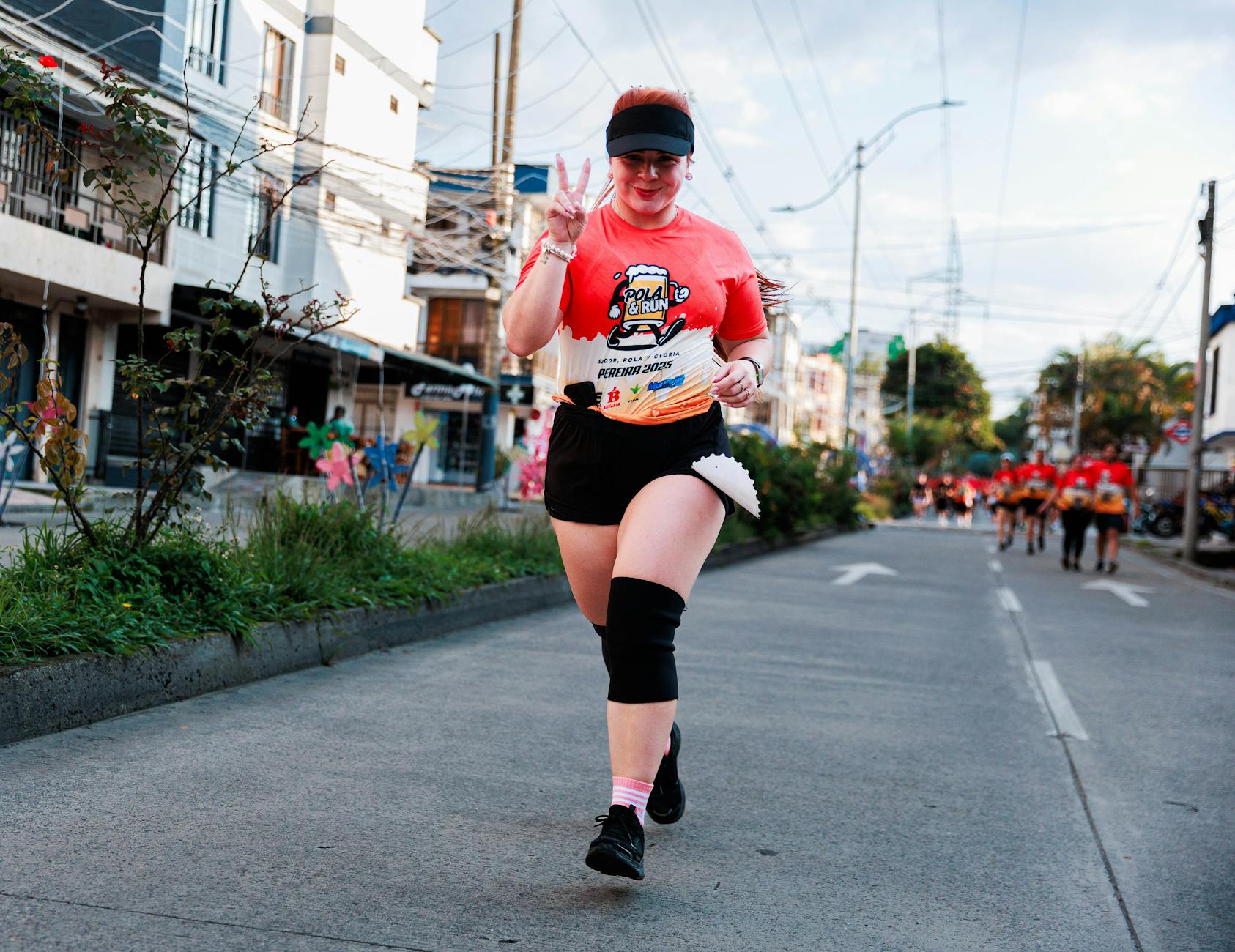 A female runner smiling and showing a peace sign during an outdoor marathon event. - marathon recovery nutrition