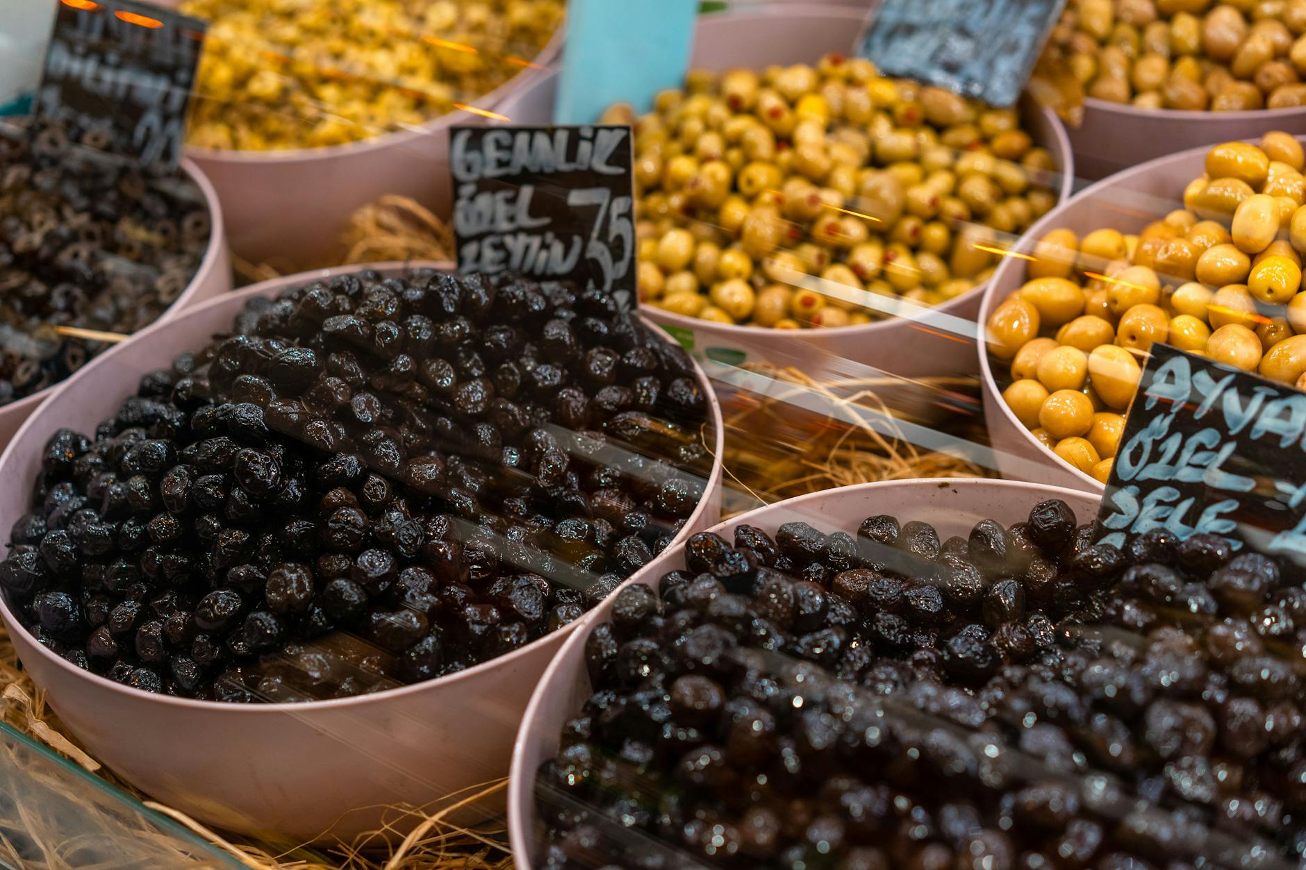 Close-up of bowls filled with different types of olives in a vibrant marketplace. - mediterranean dash diet
