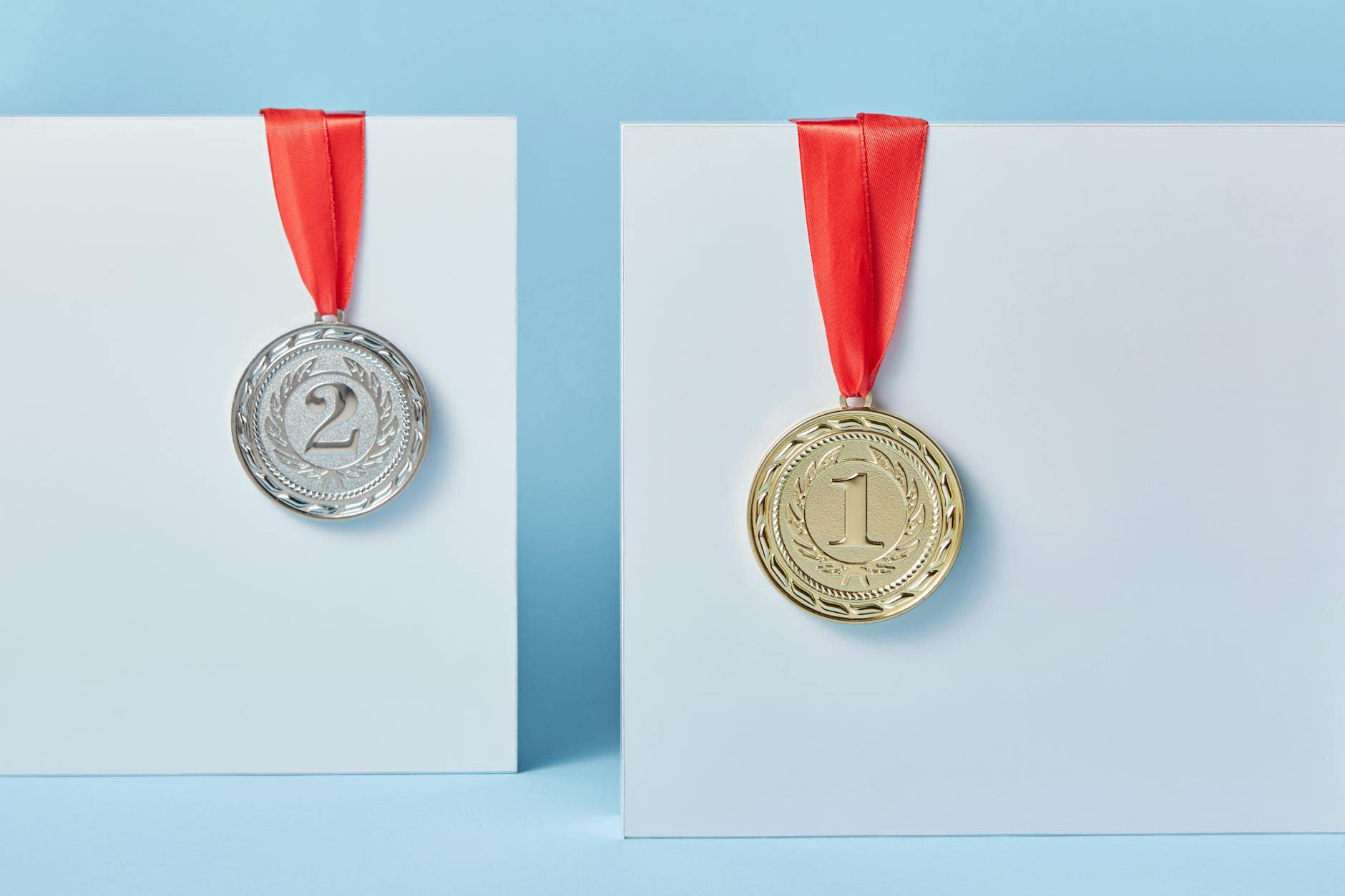 Gold and silver medals with red ribbons against a blue backdrop representing achievement and success. - non-scale victories