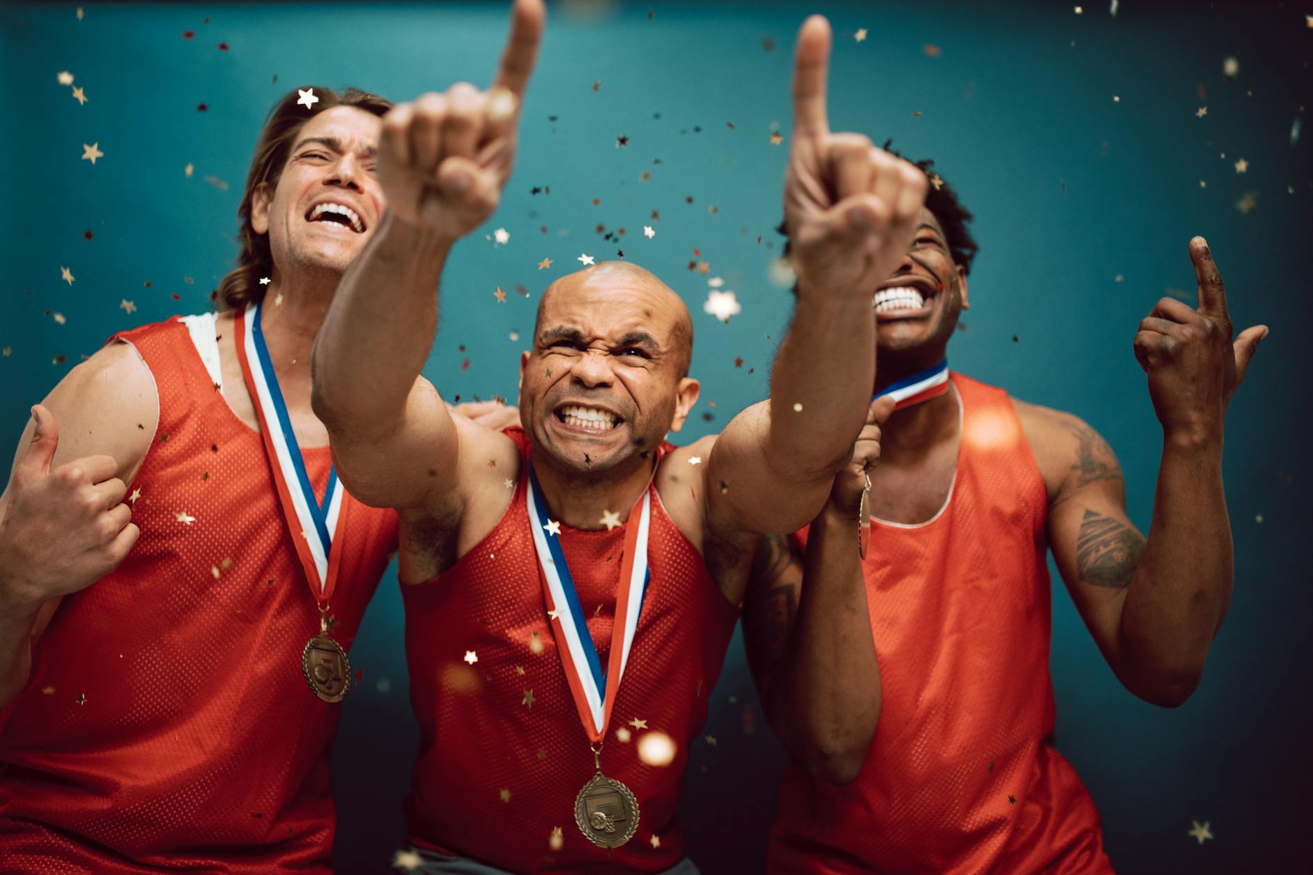 Three athletes celebrating victory with medals and confetti against a blue background. - non-scale victories