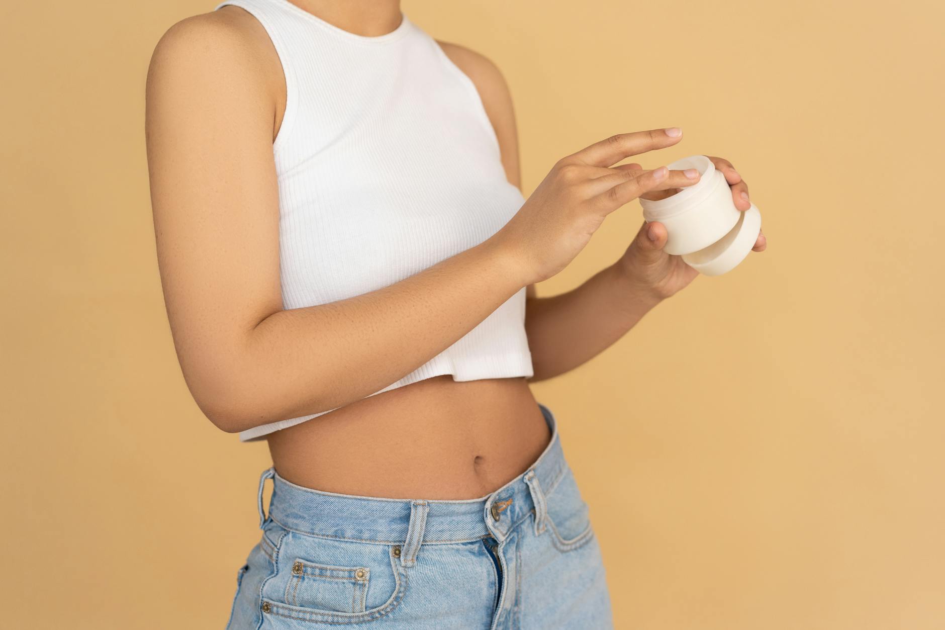 Close-up of a woman applying moisturizing cream in a studio setting with warm tones. - nourish skin from within
