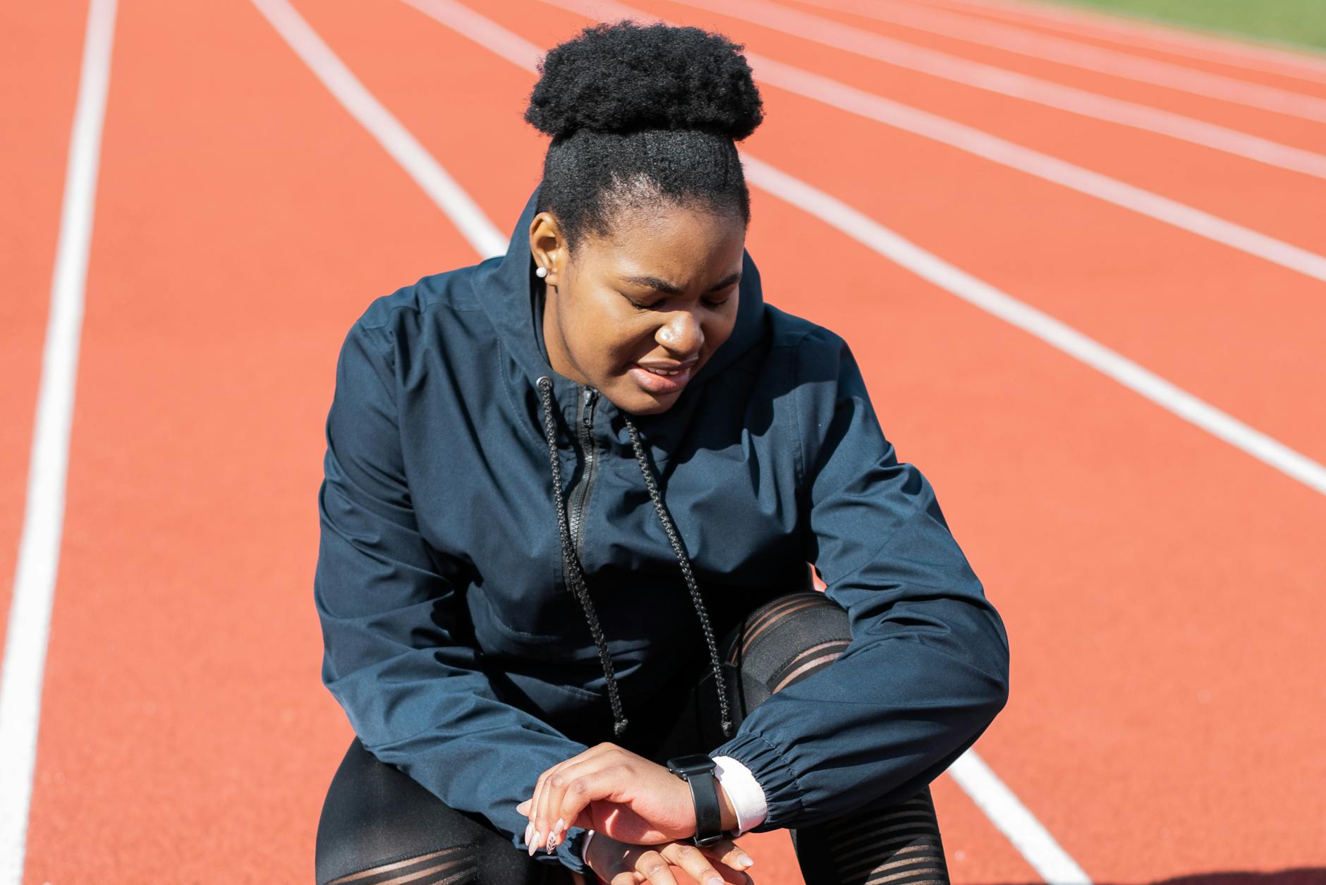 A woman in activewear on a running track checks her smartwatch after a workout. - nutrient timing fitness