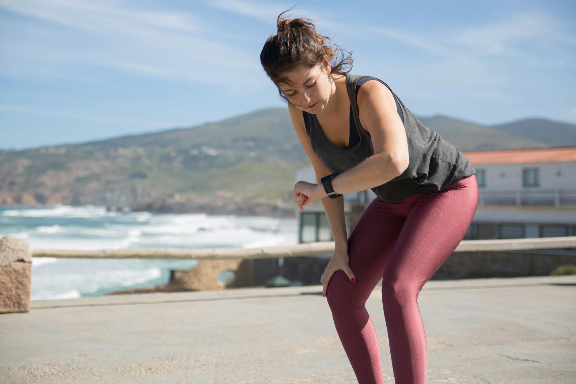 A woman in activewear checks her smartwatch while exercising outdoors by the sea. - nutrient timing fitness