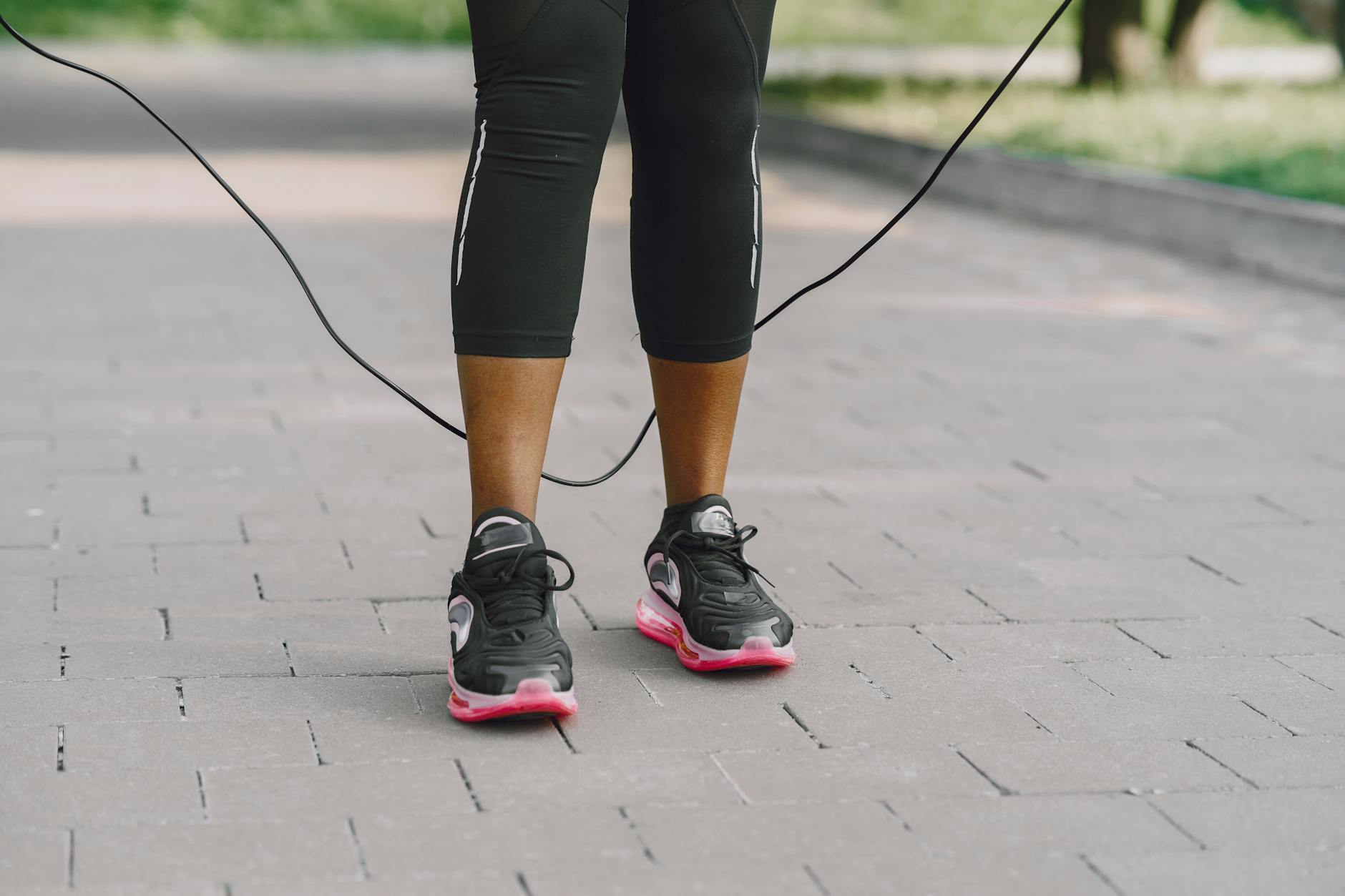 Close-up of feet in sneakers jumping rope on outdoor pavement. - outdoor cardio beginners