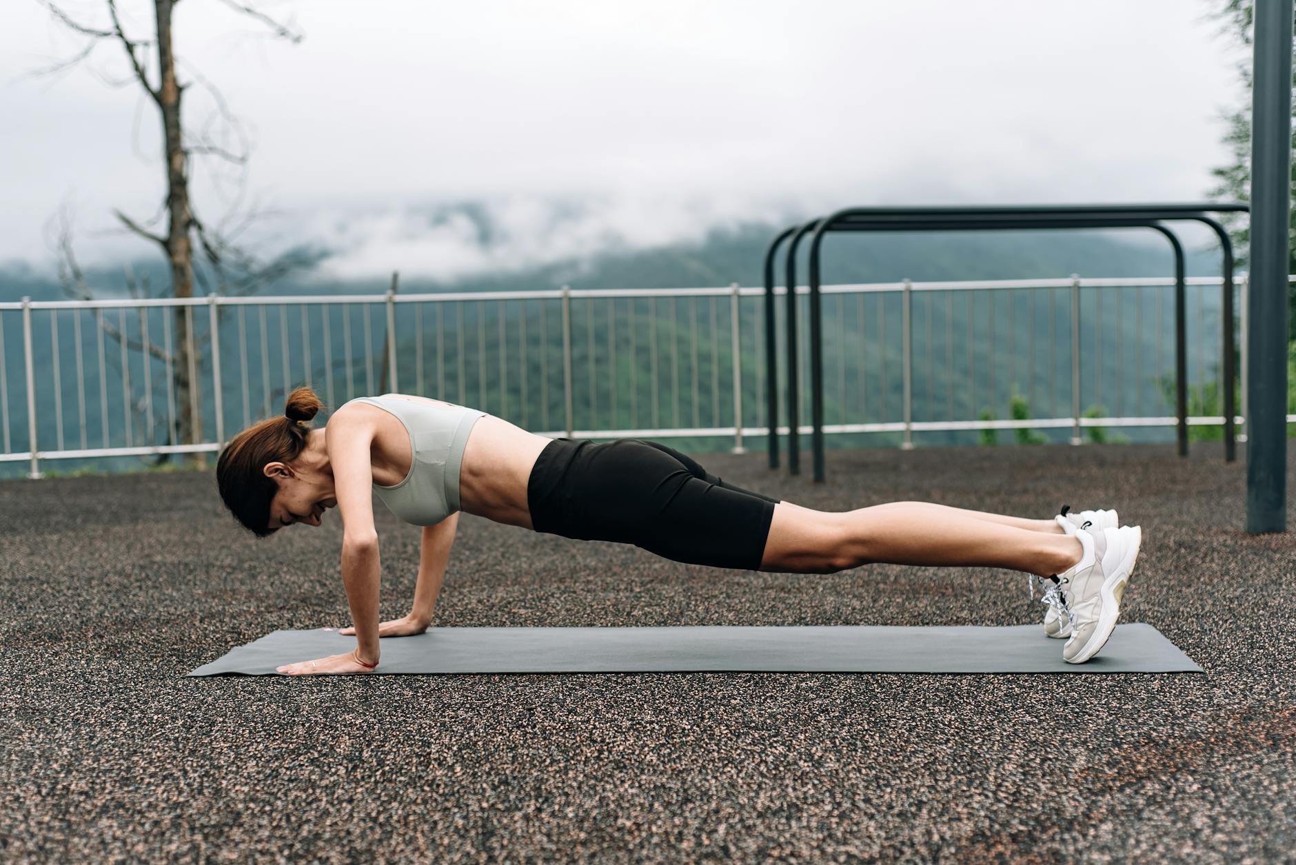 A woman in activewear doing a plank on a yoga mat outdoors, promoting fitness and strength - outdoor core workout