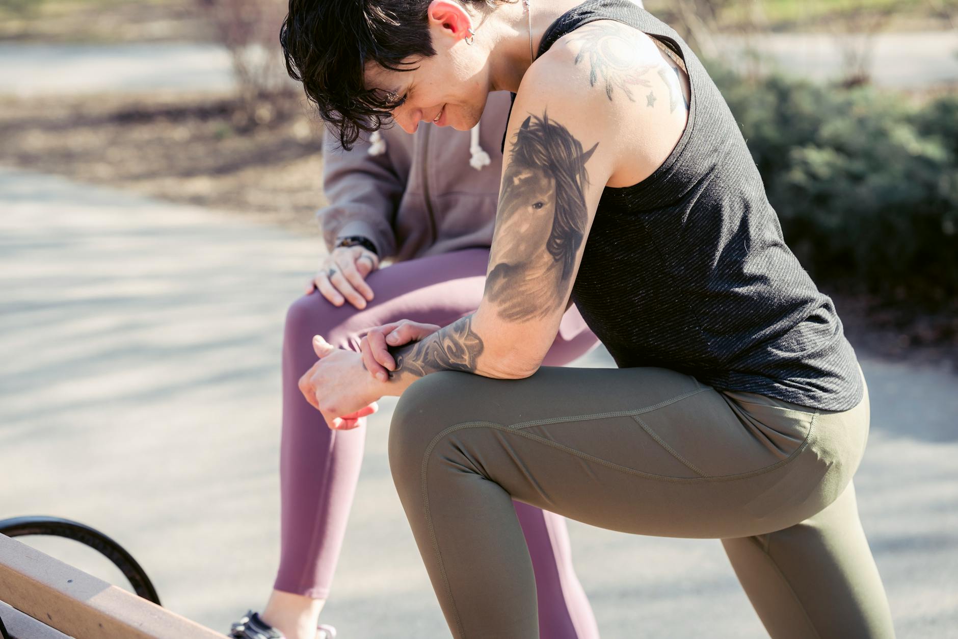 Ladies in sportswear doing exercises on bench in park near road and plants in city street in sunny day - outdoor hiit spring