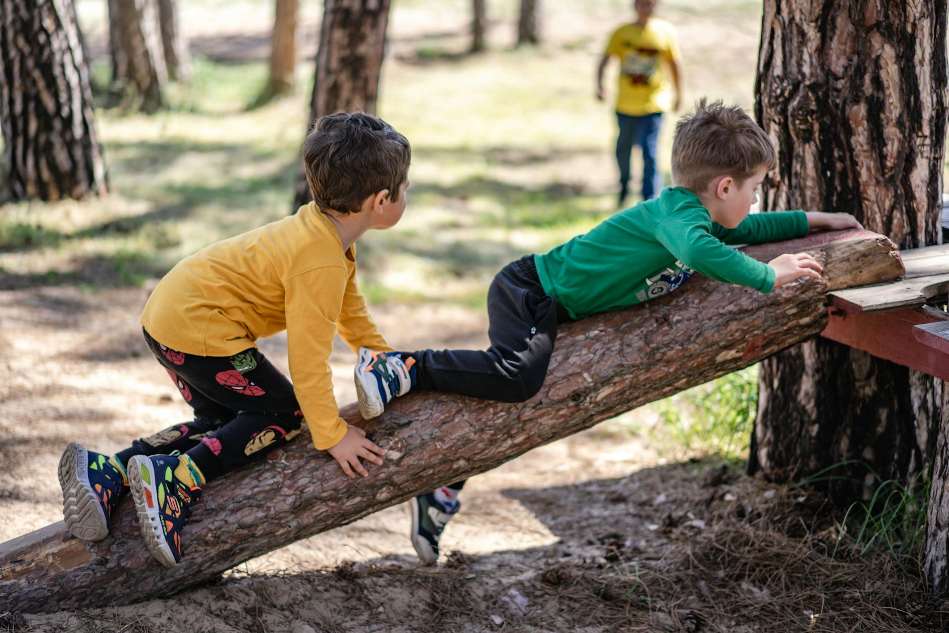 Kids enjoying outdoor play on a tree log, embodying fun and adventure. - outdoor spring activities
