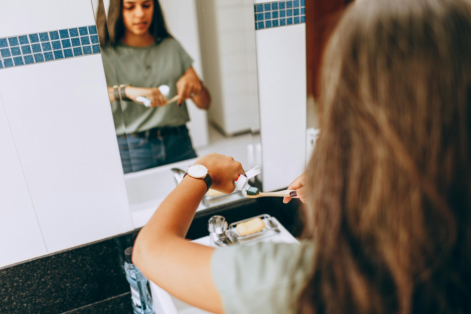 Teen girl brushing teeth in a modern bathroom, emphasizing daily hygiene routine. - personal hygiene tips