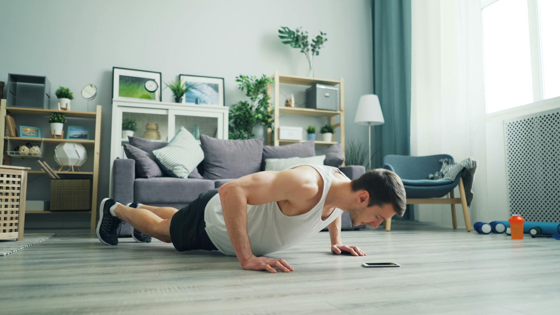 A muscular man performing push-ups in a modern living room, showcasing home fitness. - quick at home workouts