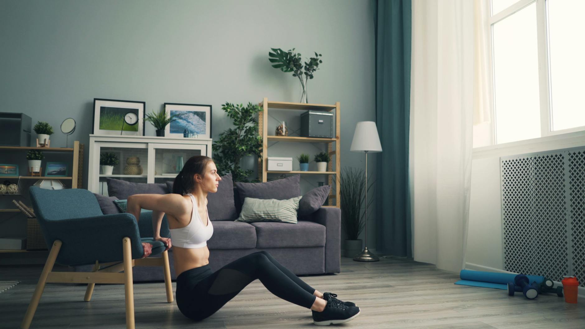 Woman doing tricep dips at home using a chair for support, promoting fitness indoors. - quick at home workouts