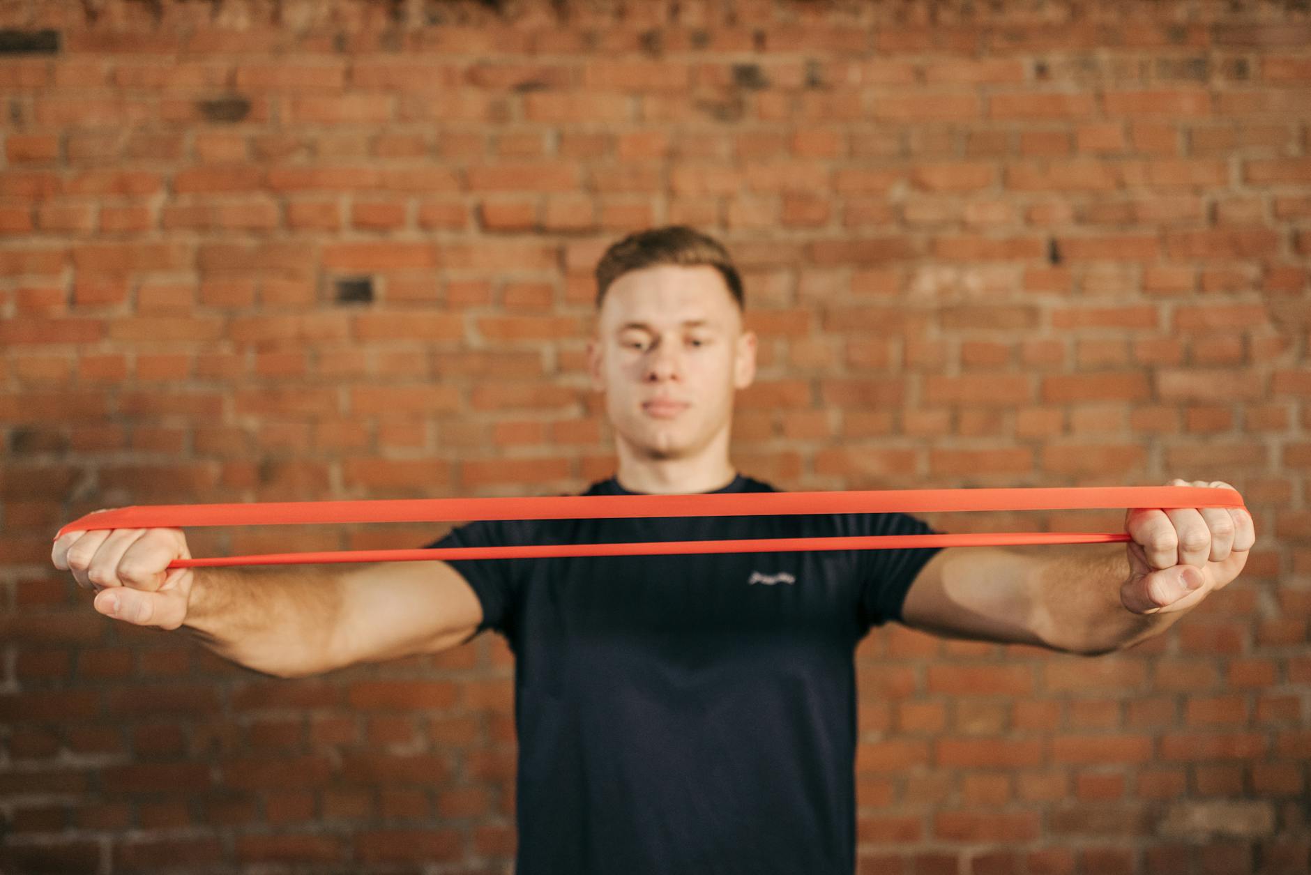 Adult male using a resistance band for fitness training against a brick wall backdrop. - resistance band abs