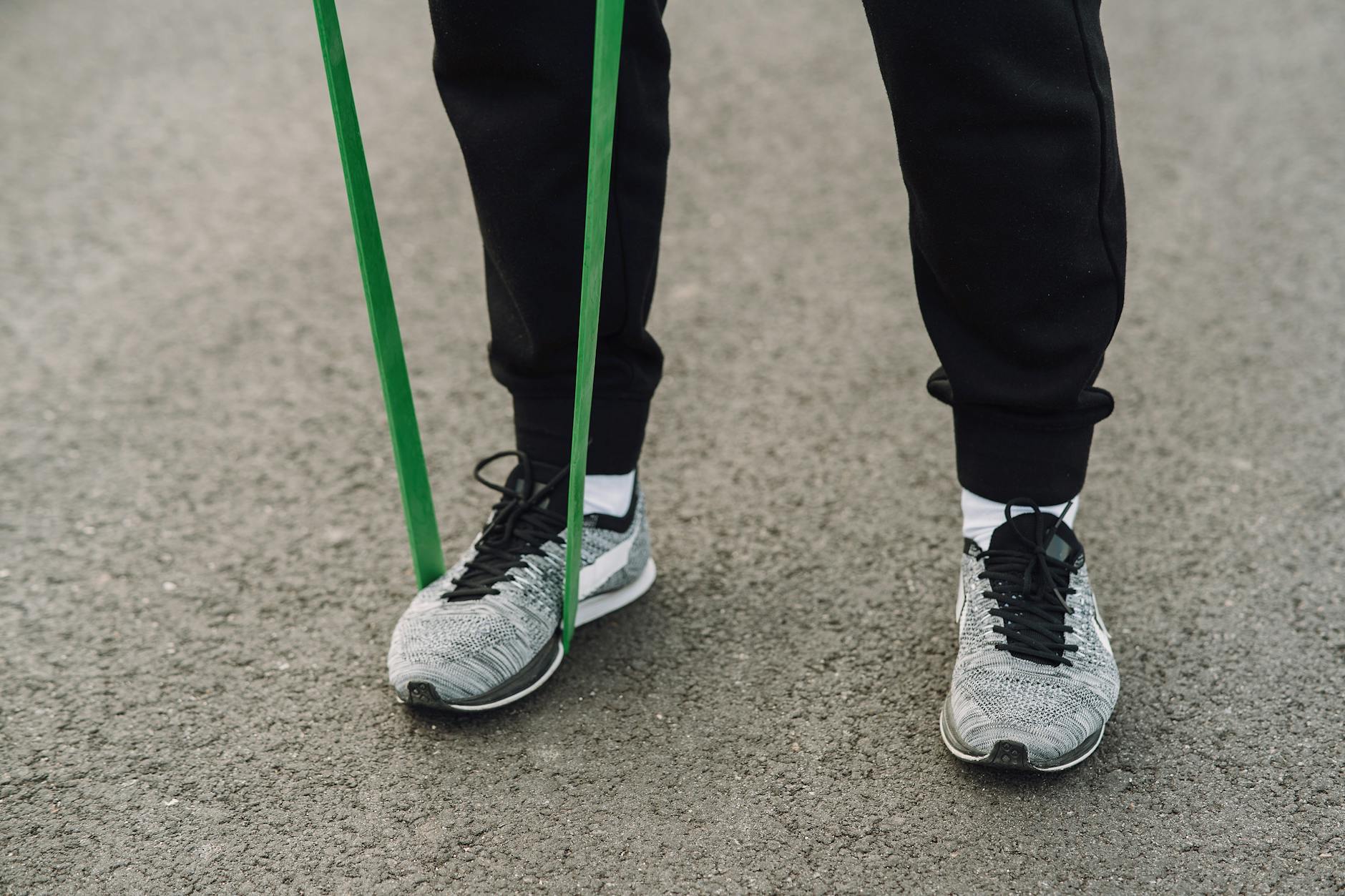 Close-up of person using a green resistance band during an outdoor workout. - resistance band abs