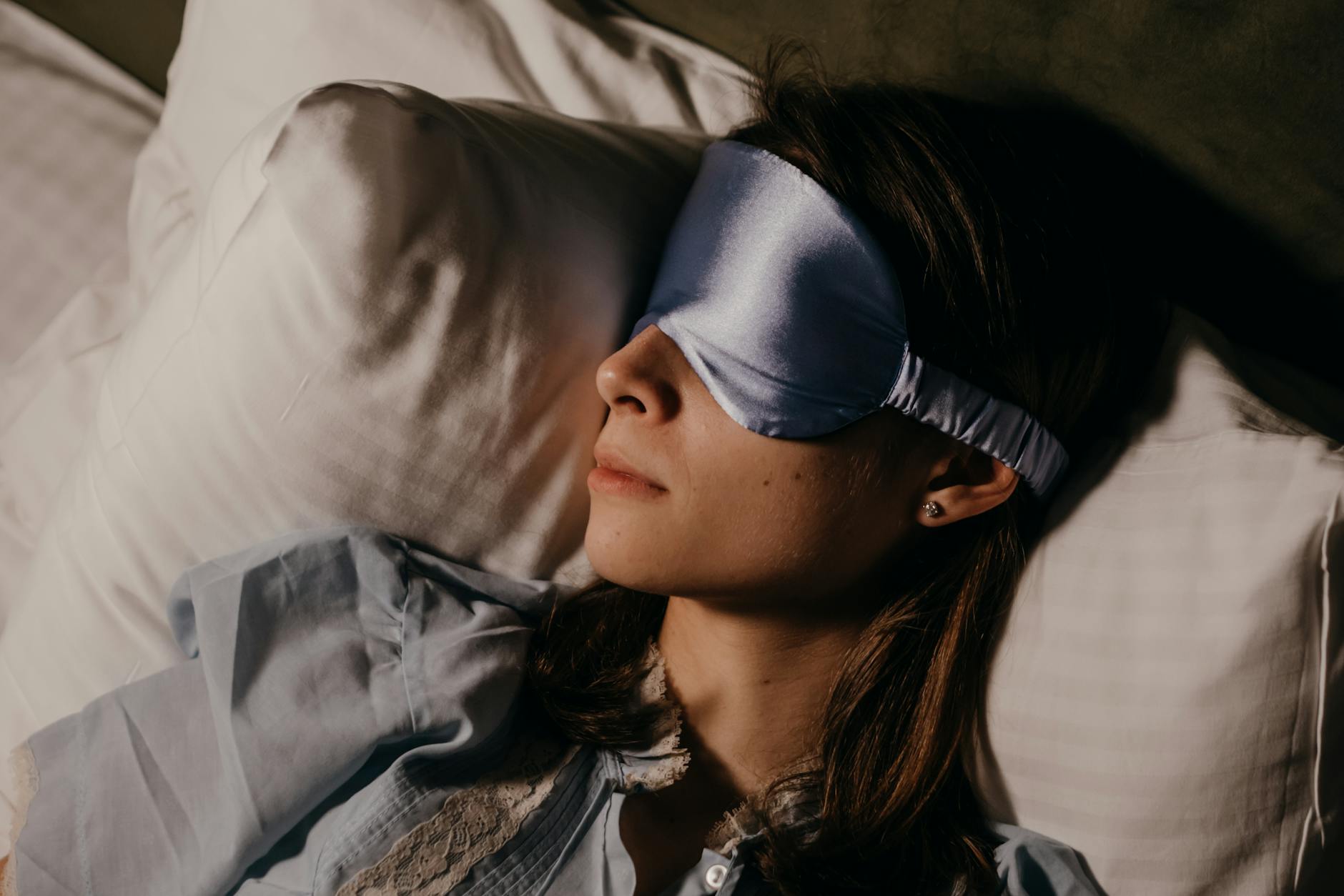 A woman peacefully sleeping indoors wearing a silk eye mask, capturing calm and relaxation. - sleep cycle reset