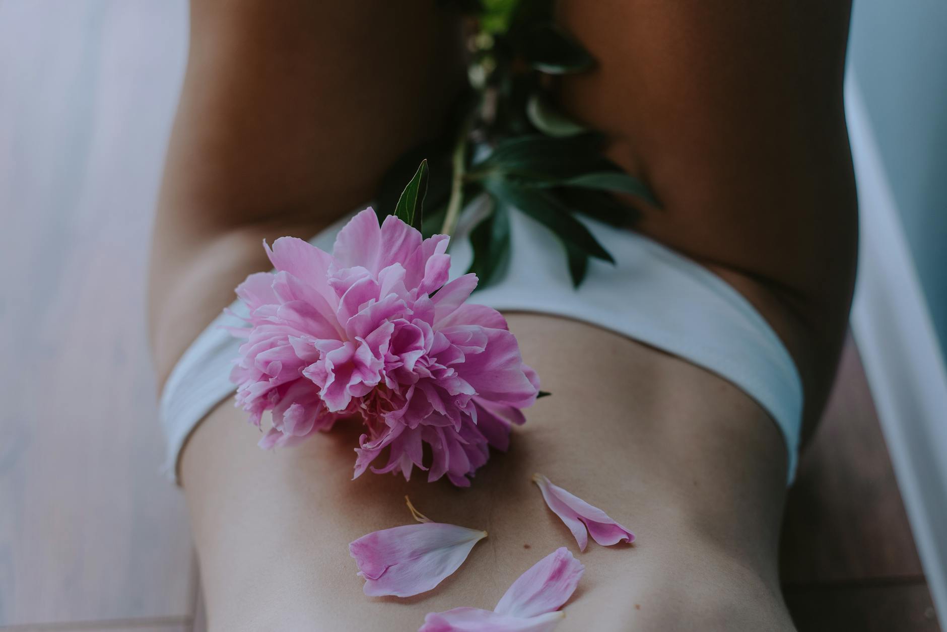Artistic image of a woman with peony flower petals on skin, capturing sensuality and elegance. - spring body reset