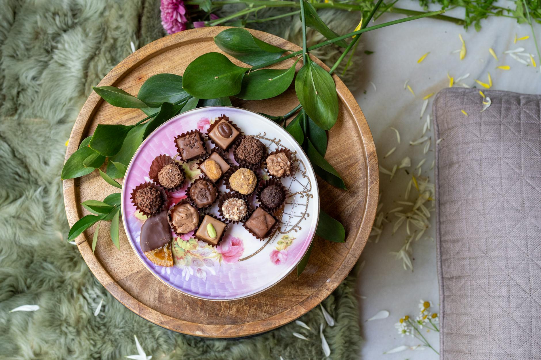A close-up view of assorted chocolates elegantly arranged on a decorative floral plate. - spring cravings explained