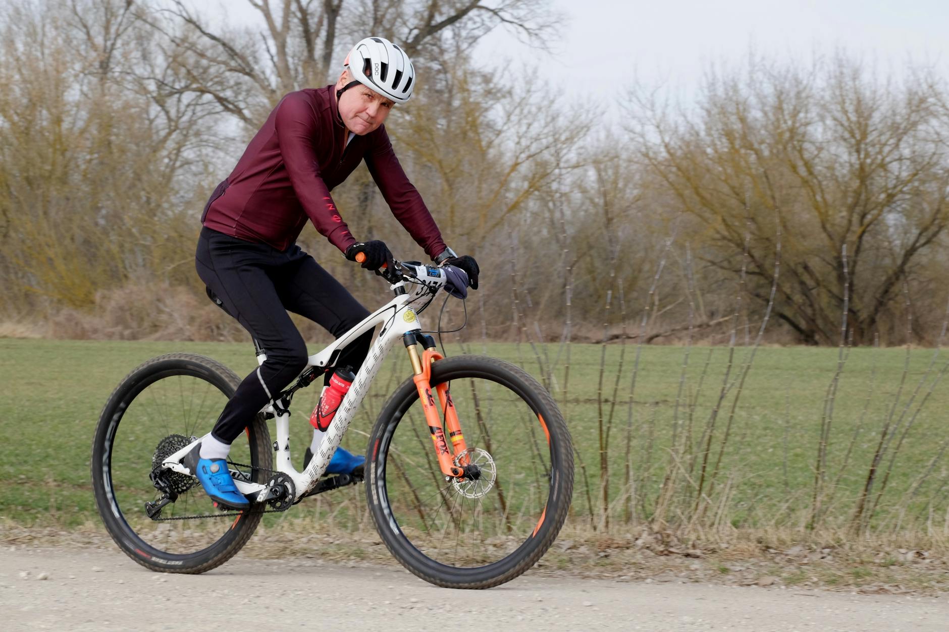 An adult cyclist riding a mountain bike on a gravel path surrounded by nature, showcasing fitness and outdoor activity. - spring cycling fitness