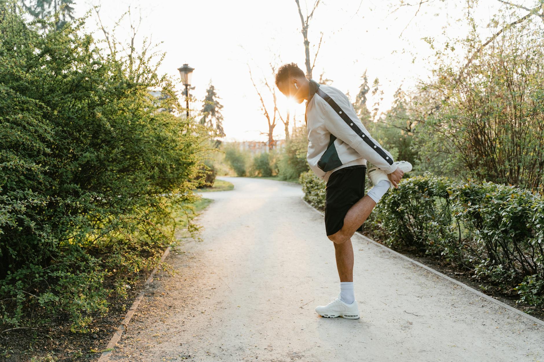 An adult man stretches in a park, enjoying a healthy exercise routine at sunrise for a fit lifestyle. - spring exercise motivation