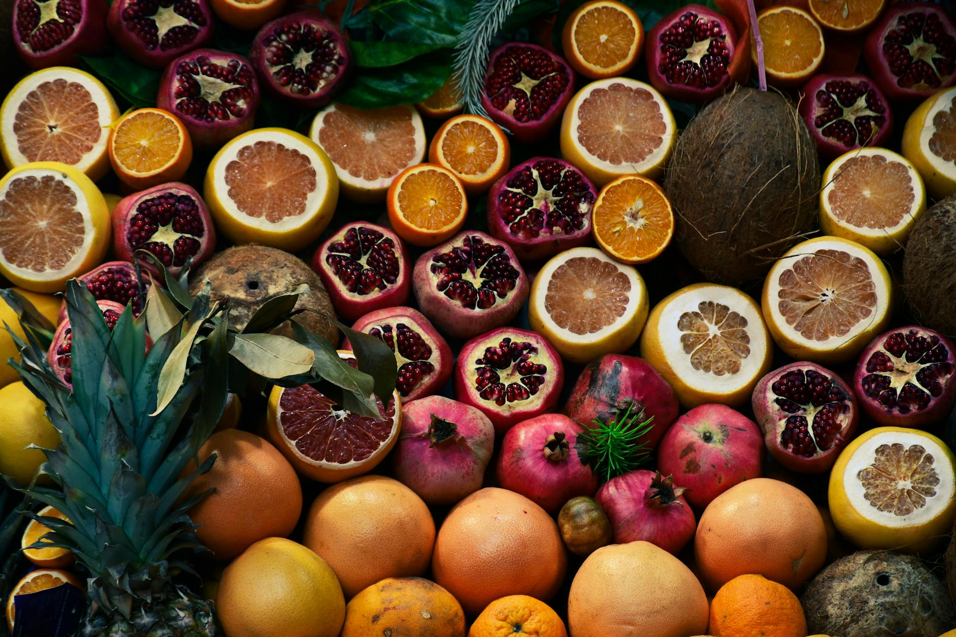 A colorful array of sliced tropical fruits including citrus, pomegranates, and coconuts. - spring fruits energy