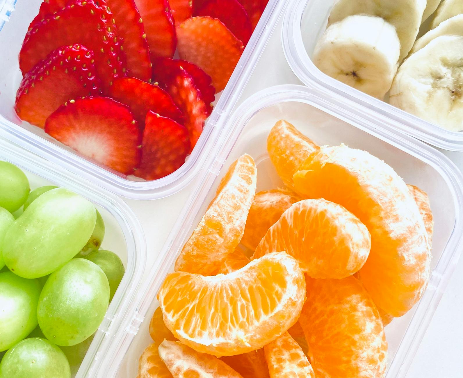 A vibrant and colorful assortment of fresh fruits in clear boxes, perfect for healthy snacking. - spring fruits energy