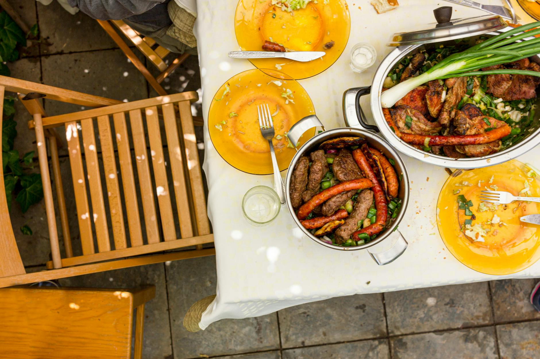 Enjoy a hearty outdoor meal featuring various grilled meats served on a set table in a garden setting. - spring garden meals