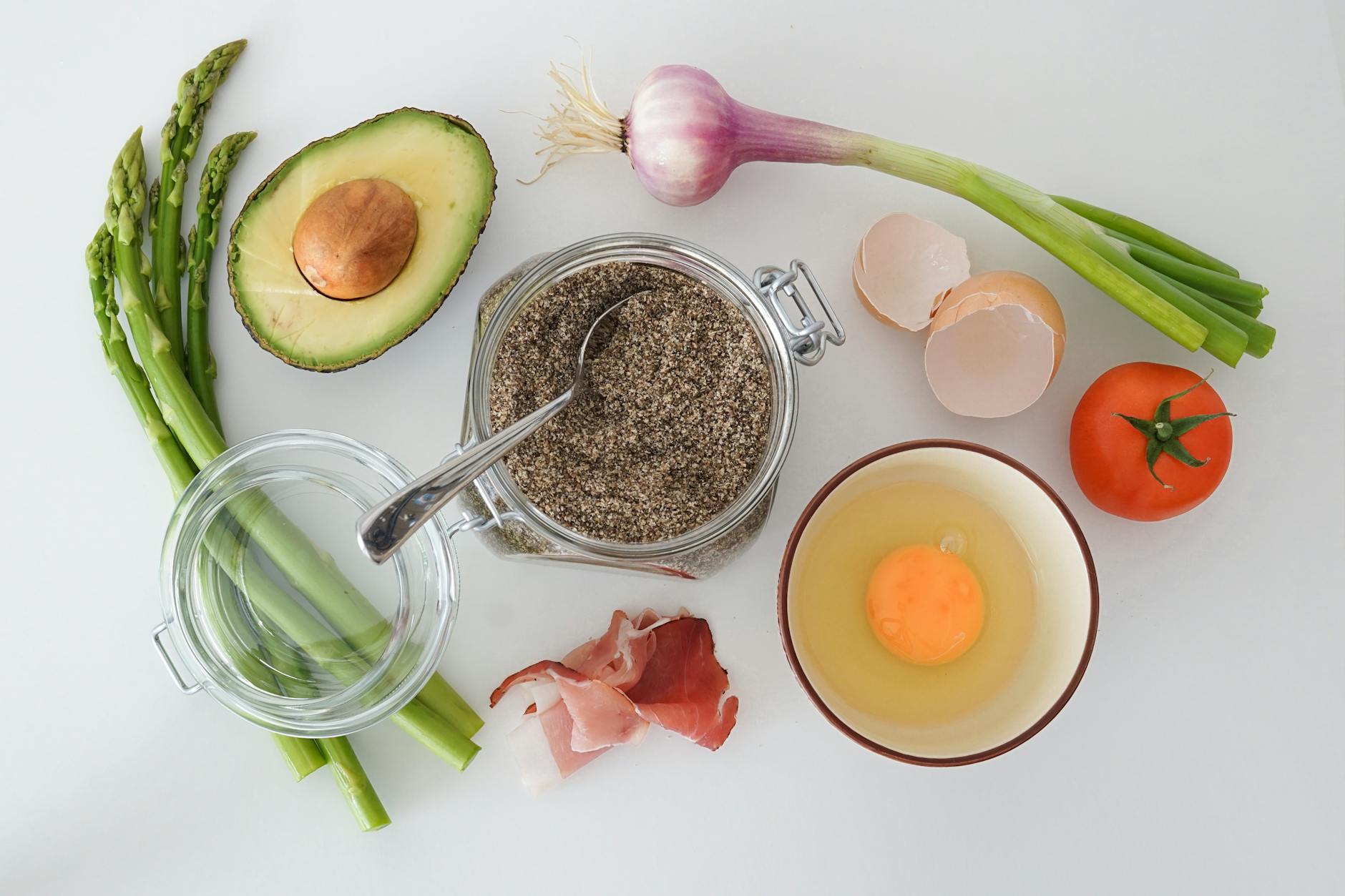 Flat lay of fresh asparagus, avocado, egg, tomato, and more for a keto-friendly dish. - spring healthy recipes