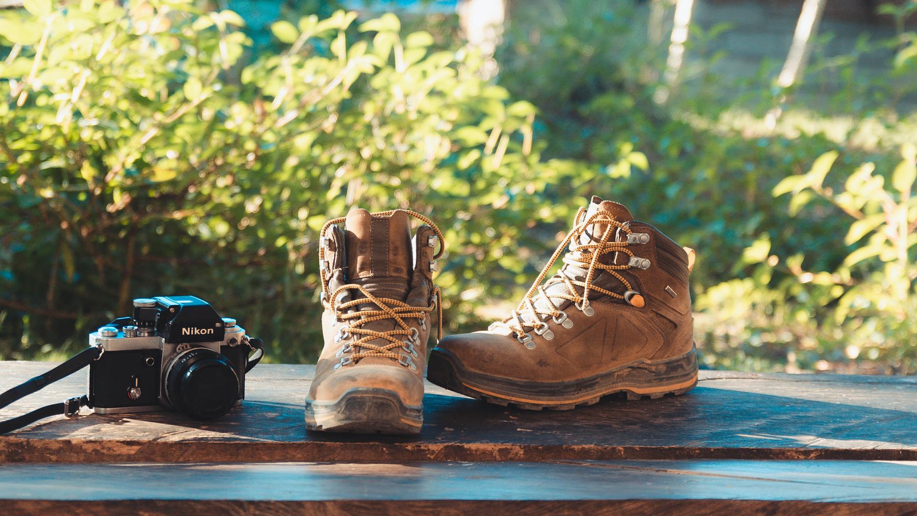 Outdoor hiking scene with boots and camera on a wooden surface, perfect for adventure themes. - spring hiking essentials