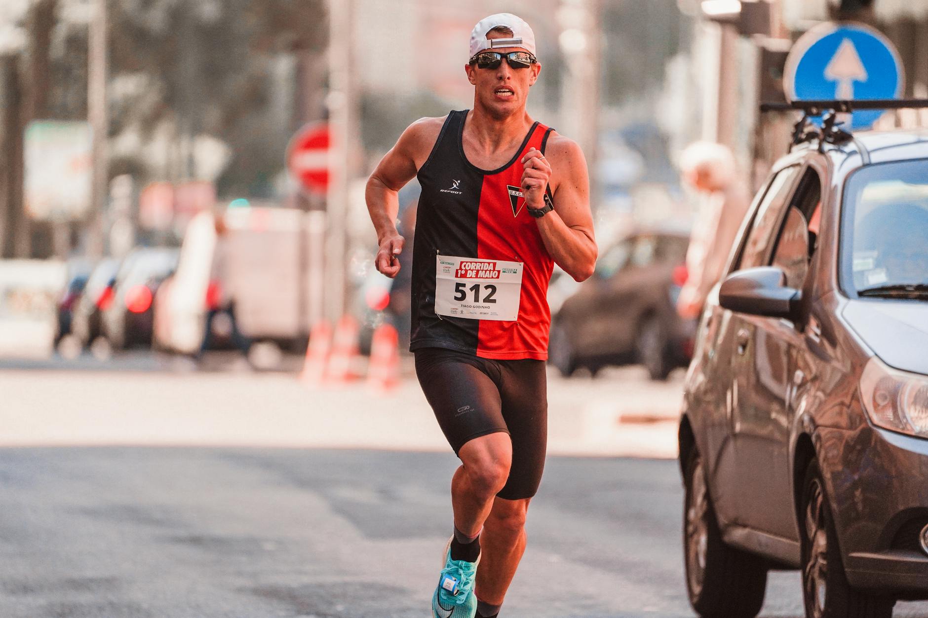 Athletic man wearing a cap and sunglasses competing in a marathon on urban streets. - spring marathon training