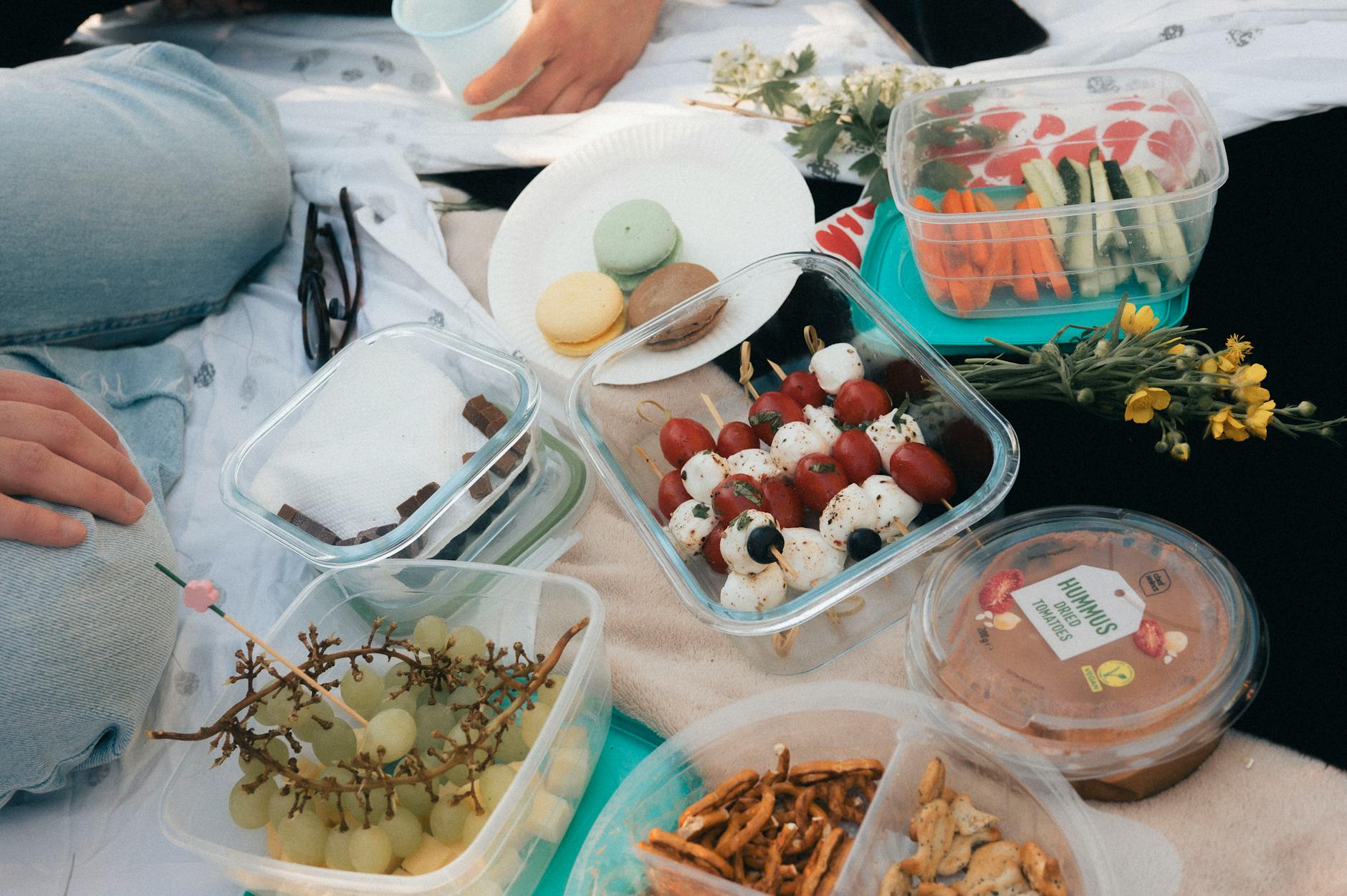 A delightful picnic setup with fresh fruits, vegetables, hummus, and macarons on a sunny day. - spring meal plan