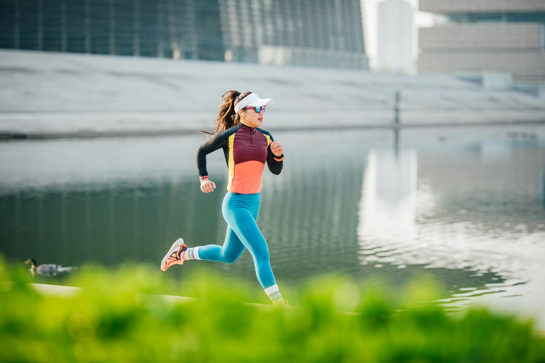 Athletic woman jogging in vibrant sportswear by an urban lakeside setting during the day. - spring run nutrition