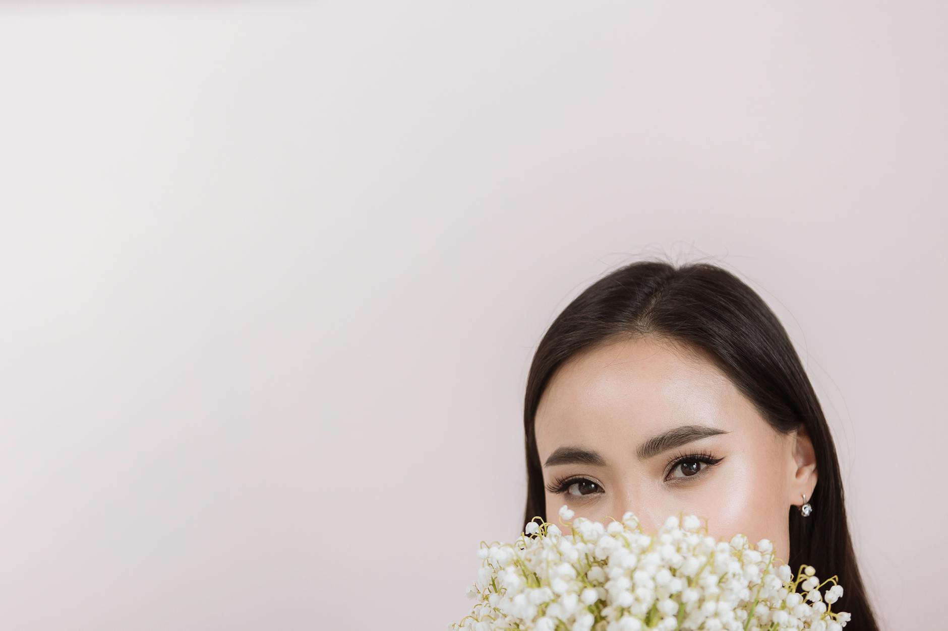Elegant portrait of a woman with flowers covering her mouth, floral focus. - spring skin glow