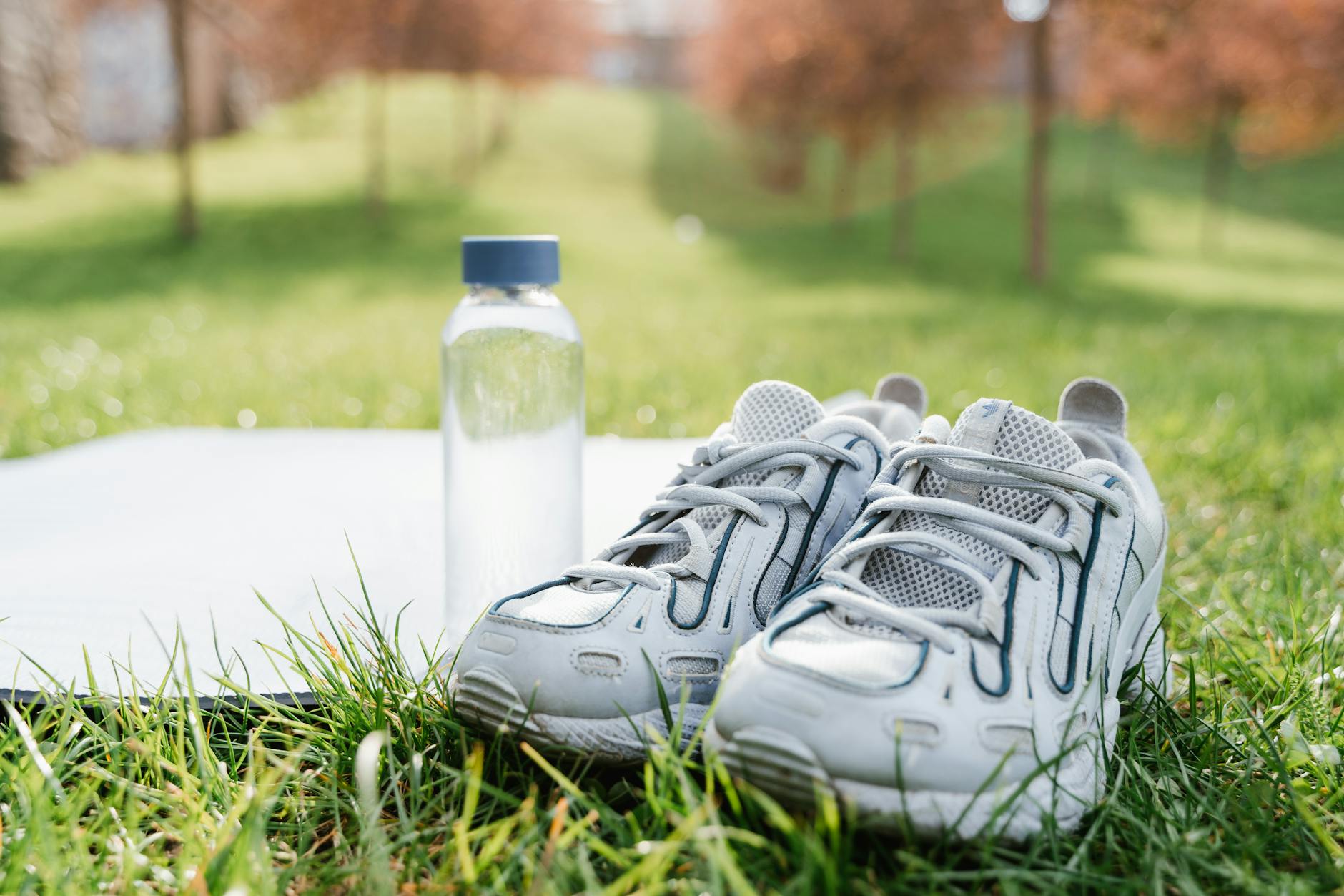 A close-up of white sneakers and a water bottle, ideal for sporty lifestyle themes. - spring sports hydration