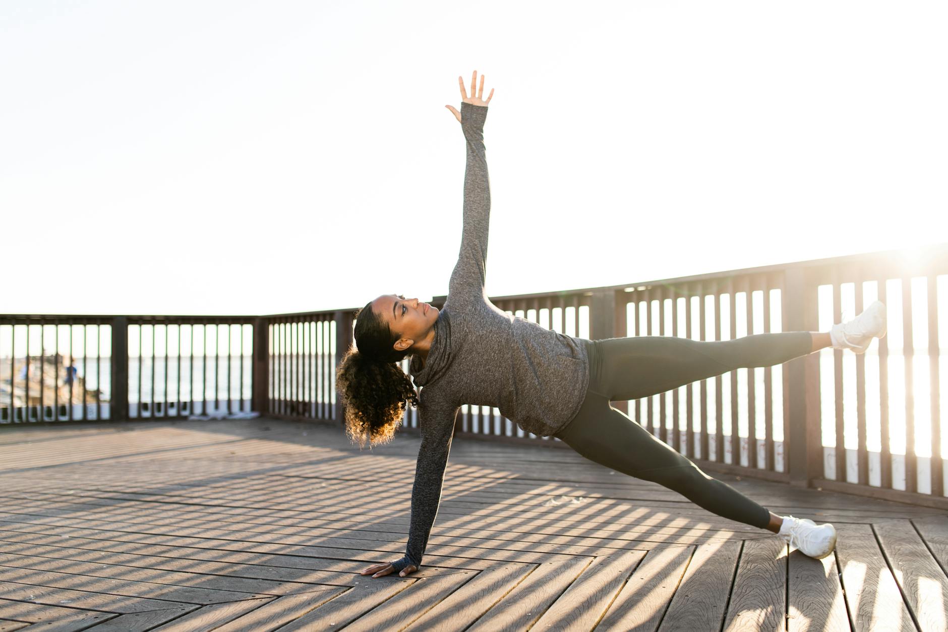 African American woman doing yoga side plank on a sunny day outdoors. Focused and serene. - spring strength moves