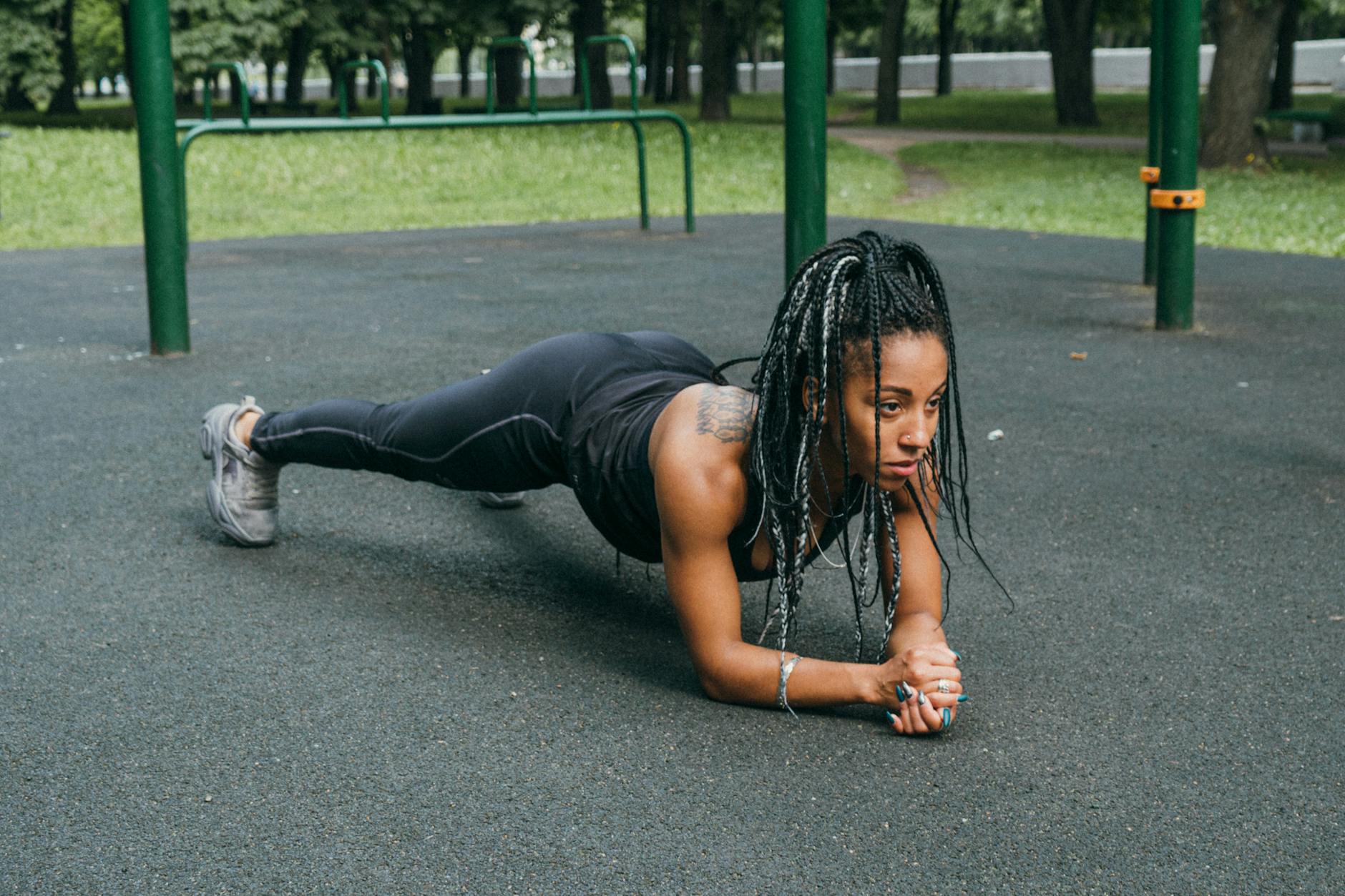 African American woman doing a plank exercise outdoors in a park, promoting fitness and healthy lifestyle. - spring strength moves