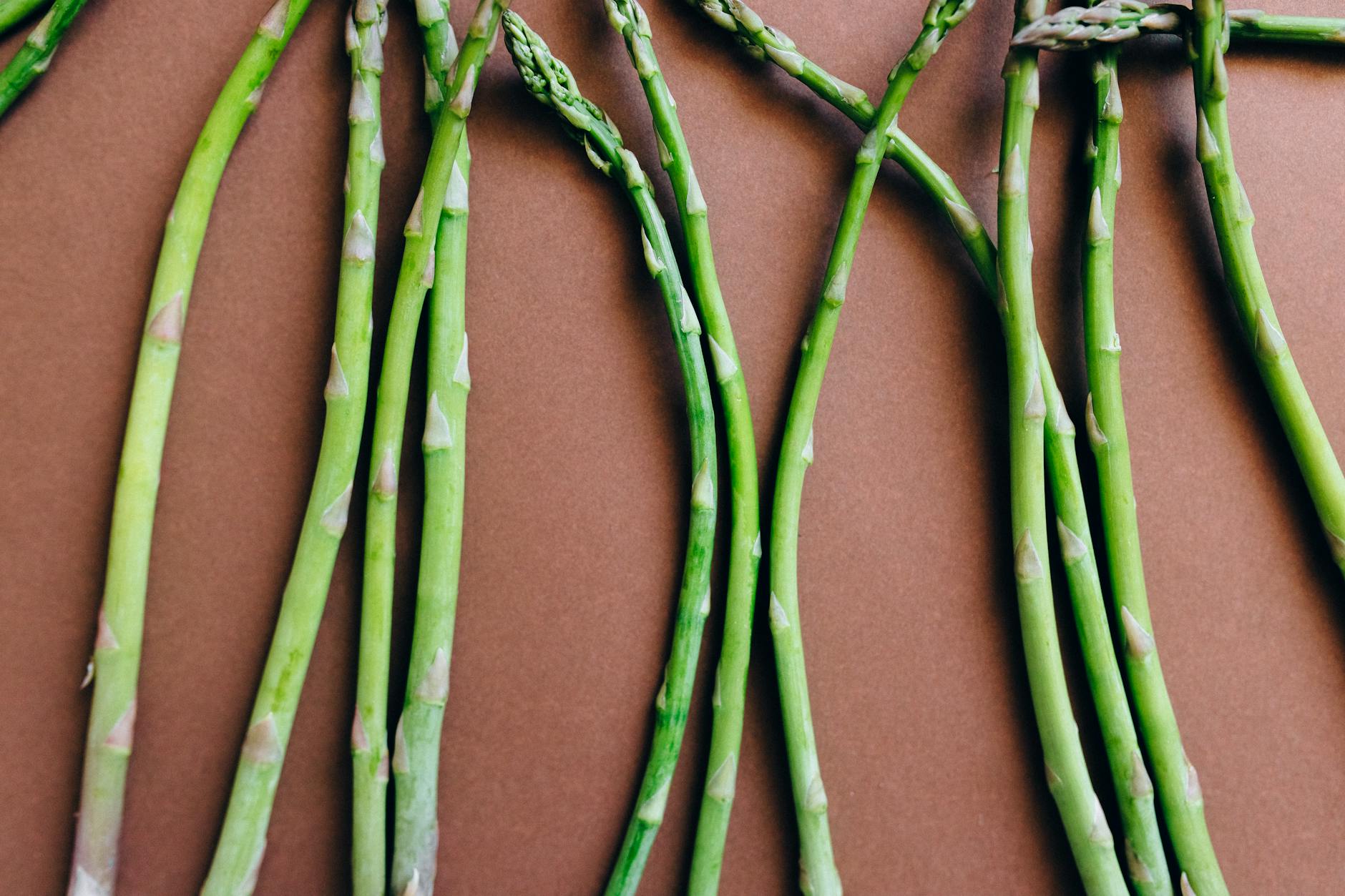Top view of fresh organic asparagus arranged on a brown background. - spring superfoods energy