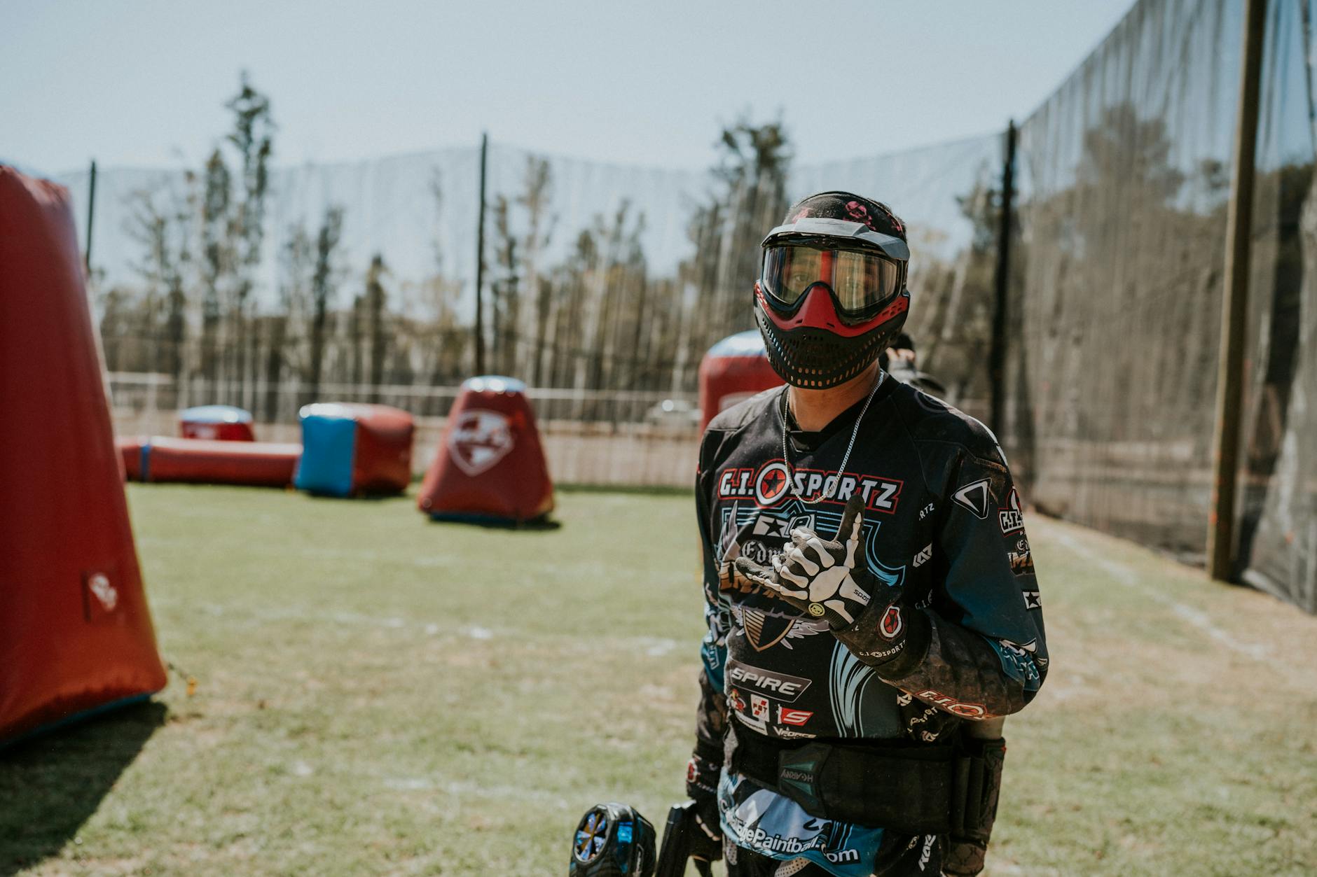 Paintball player in full gear and mask standing on an outdoor field ready for a match. - spring training gear