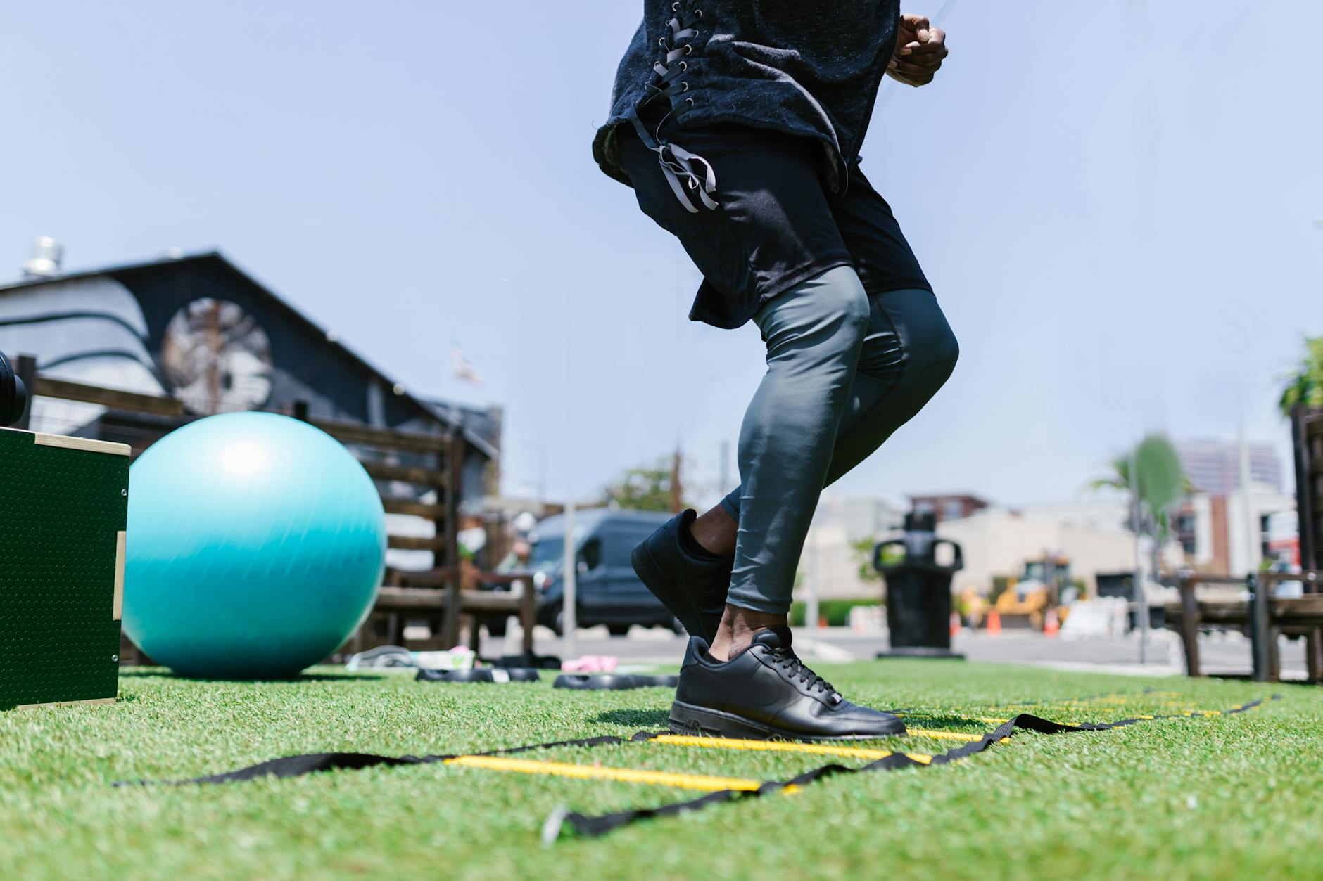 Person exercising outdoors with fitness gear and agility ladder on grass. - spring training gear