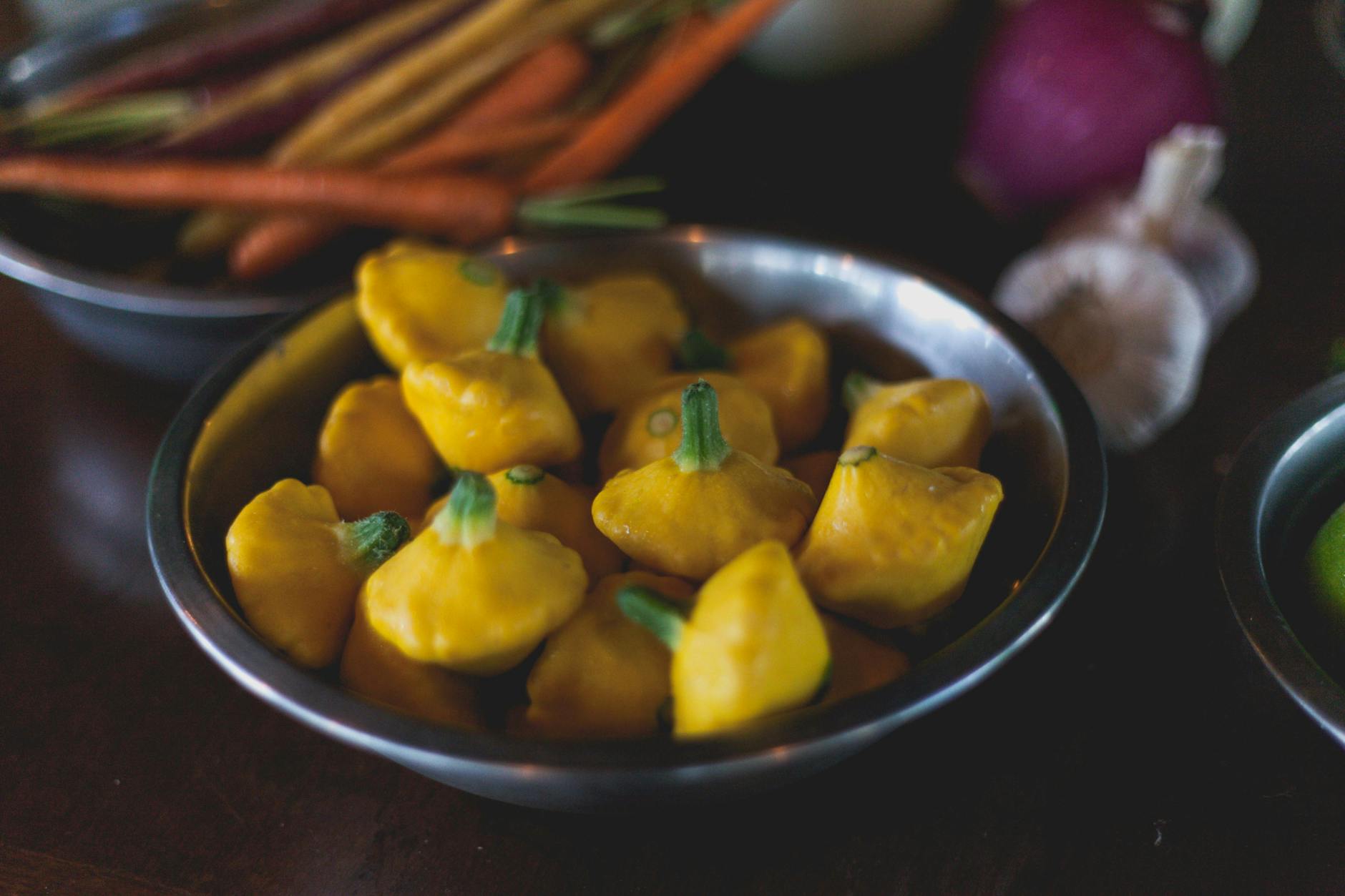 Close-up of fresh yellow patty pan squash in metal bowl with vegetables. - spring veggie bowls
