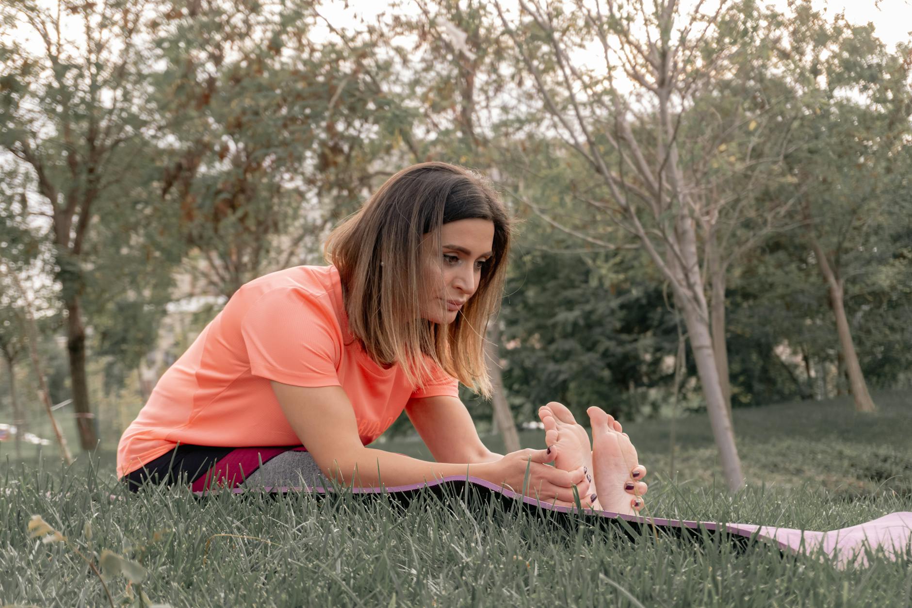 A woman performs a stretching exercise in a park on a sunny day, promoting outdoor fitness and wellness. - spring wellness routines